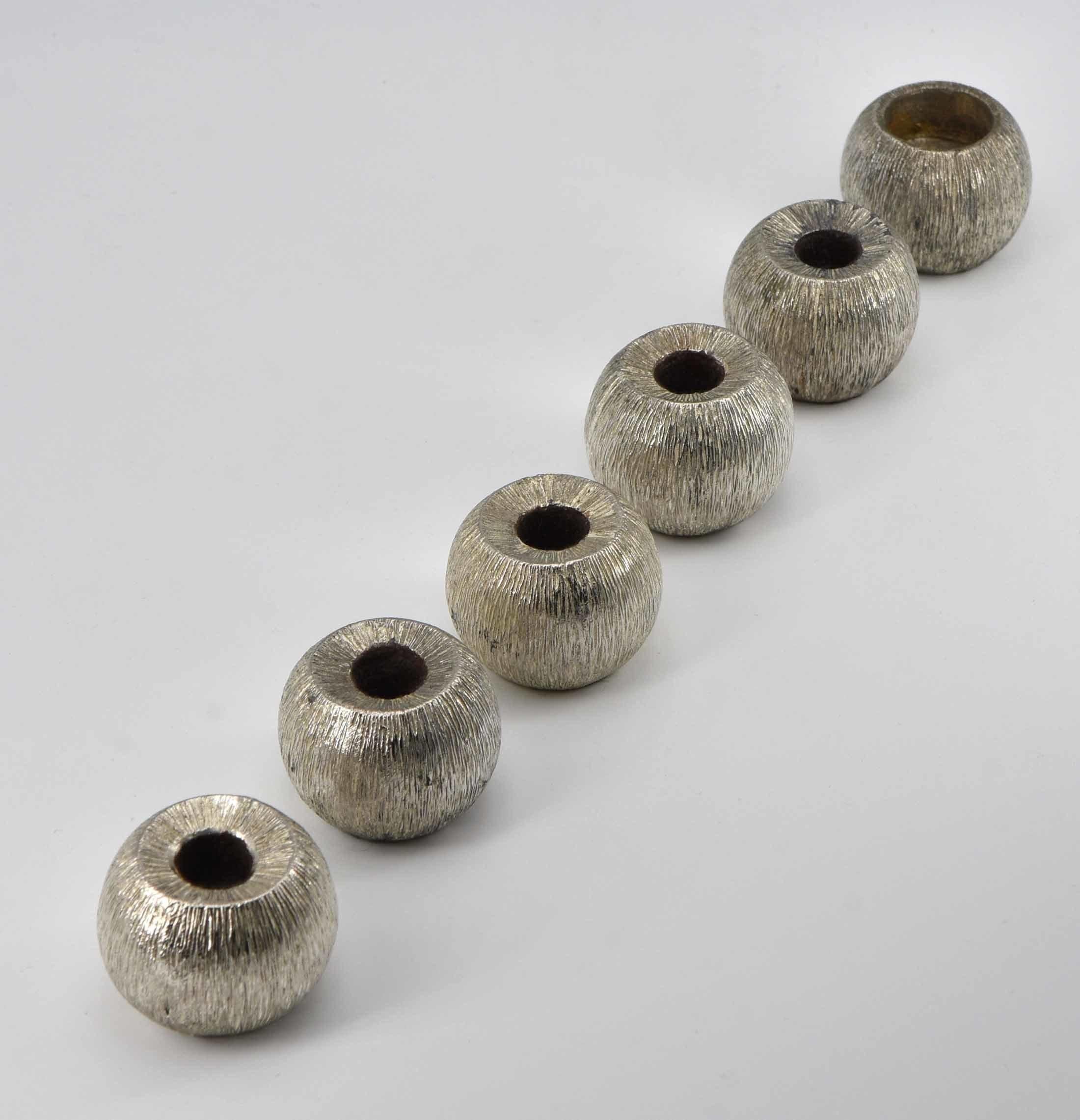Six textured bark decorated small candle holders, in the Gerald Benney manner. Circa 1970.

Five with the same candle dimension (12mm) , one larger (20mm). The holders have brown baize to the undersides except for one missing. The smaller