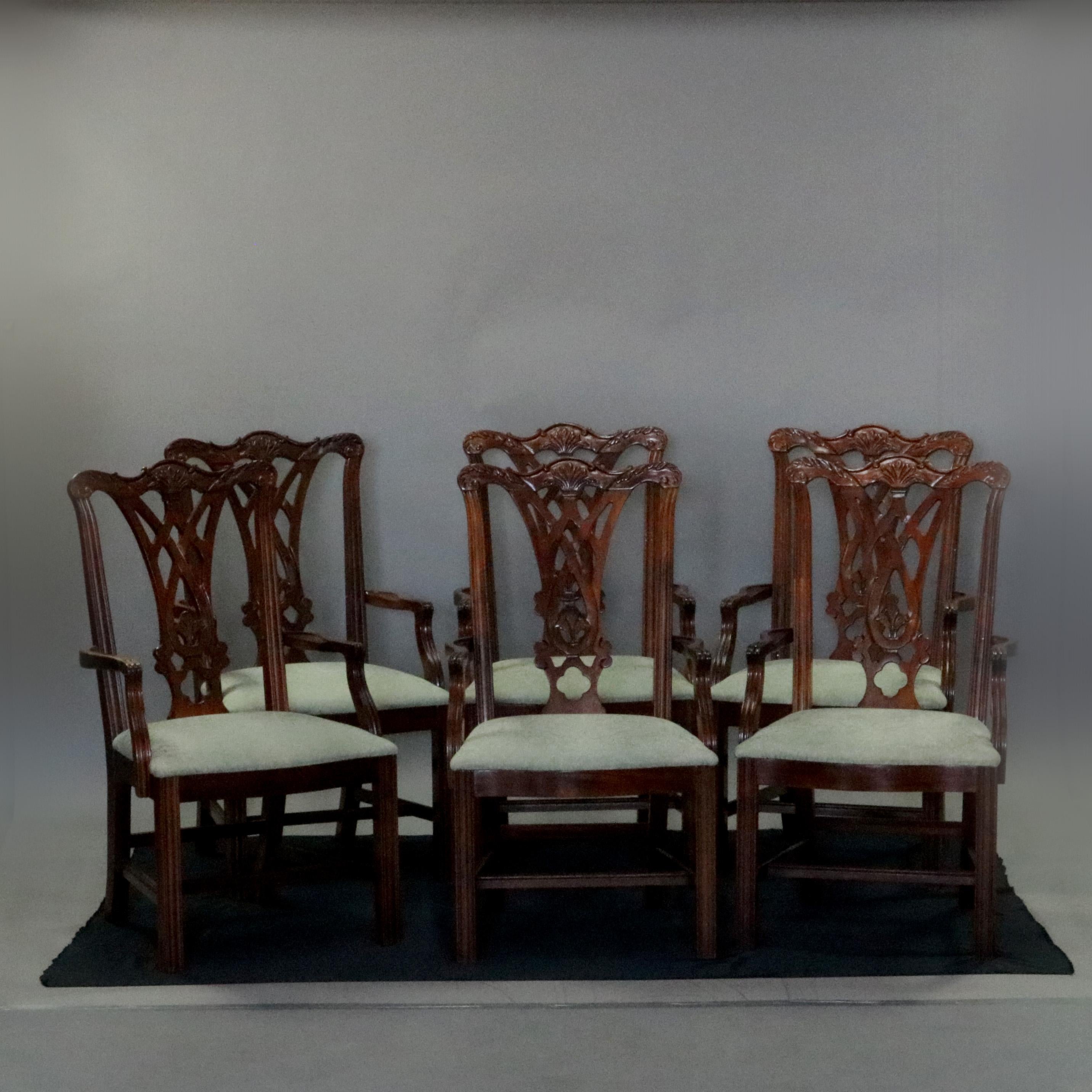 A set of 6 Chippendale style dining arm chairs feature caved mahogany frames with caved ribbon backs having foliate crests, upholstered seats and raised on straight legs, circa 1930

Measures: 40