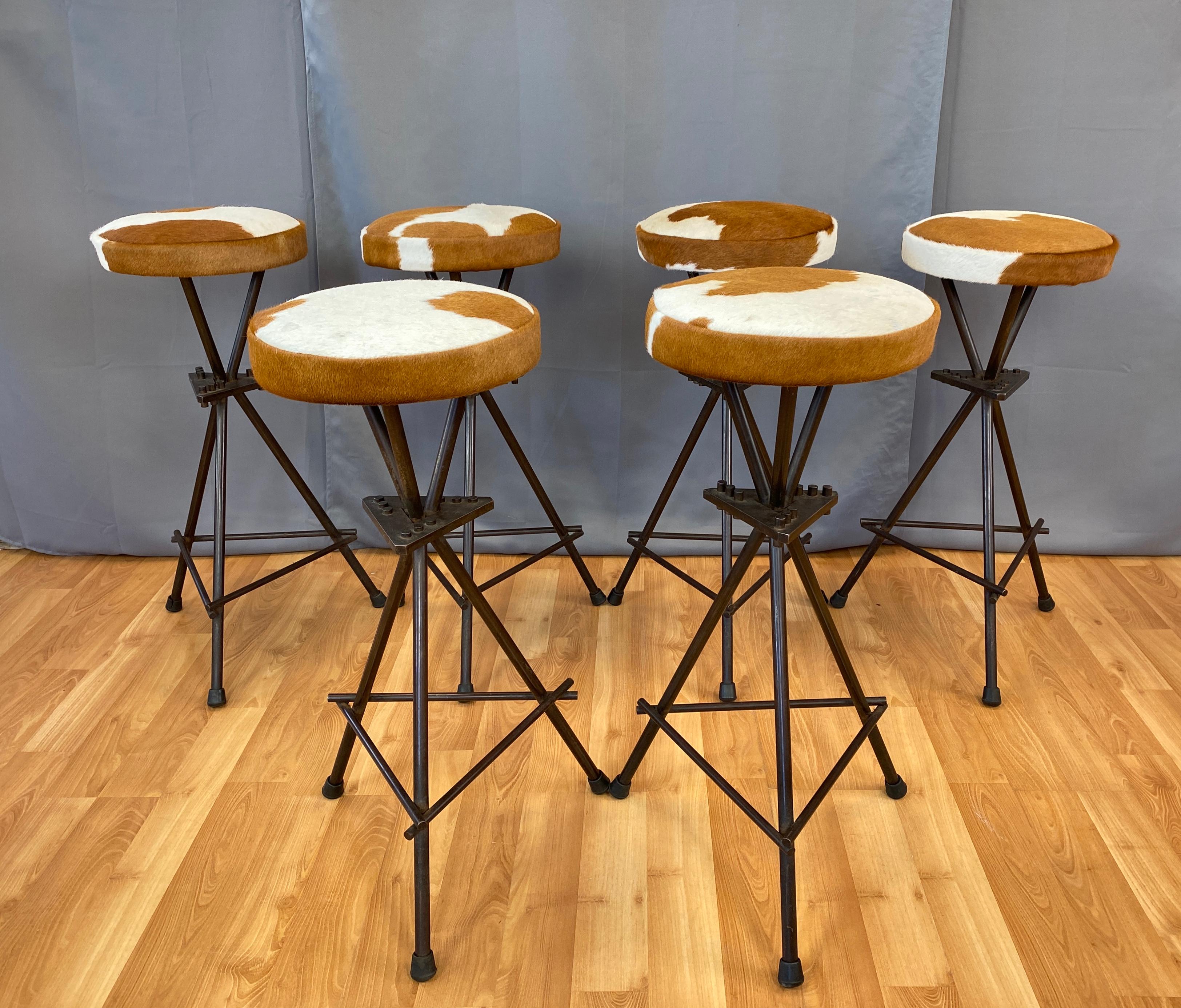 Offered here is a set of six constructivist wrought iron bar stools. 
Patinated bronze wrought iron, then oil finished. New cowhide upholstery seats (seats are non-swiveling). 
We feel these were most likely offered to the trade/custom made, and