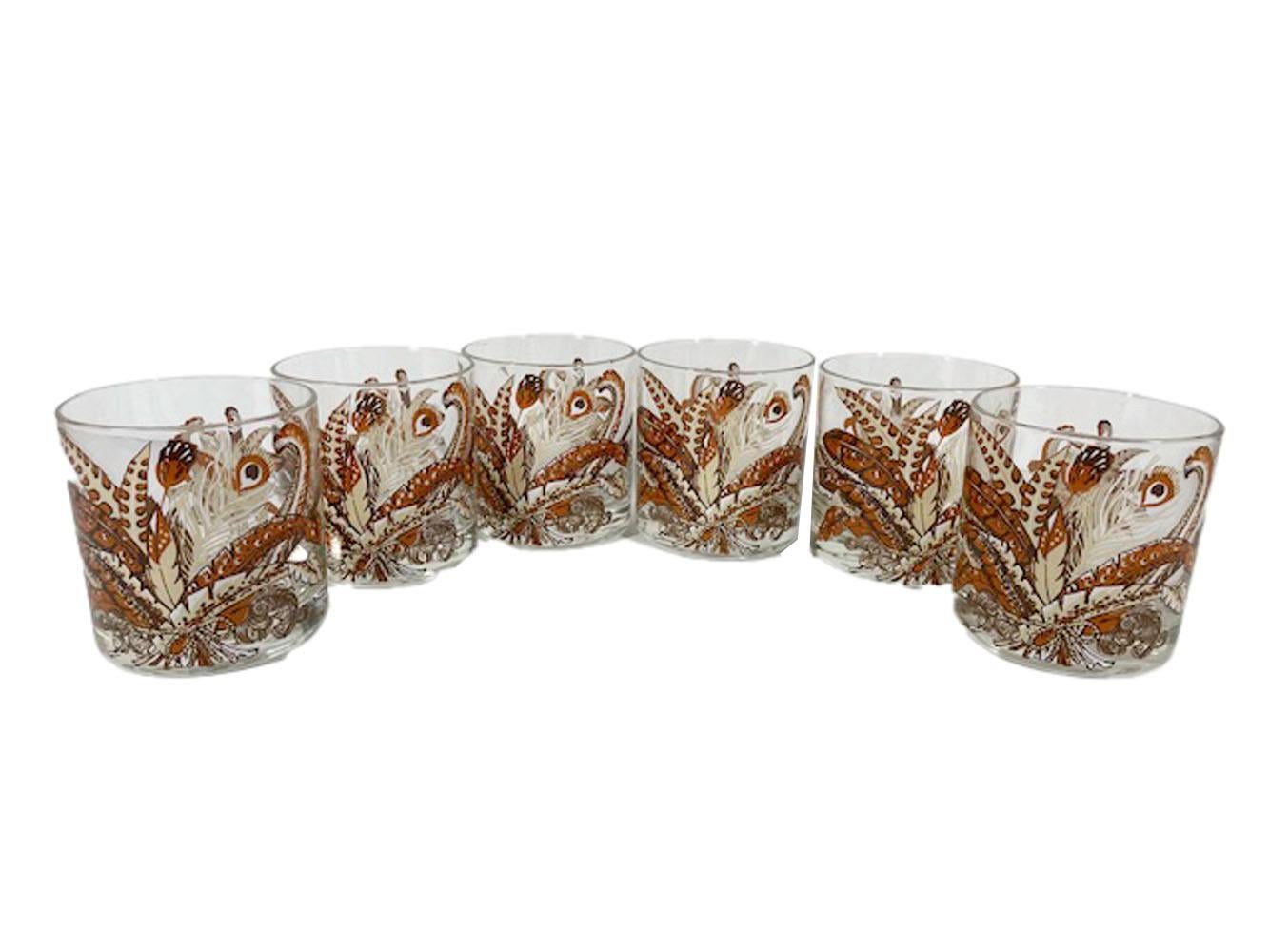 Mid-Century Modern rocks glasses designed by Georges Briard having an arrangement of exotic feathers in white, cream, tan and brown enamel.