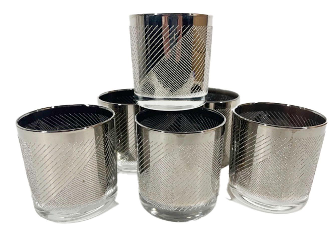 Six silver decorated glasses with a smooth surface above triangular panels of raised textured lines.