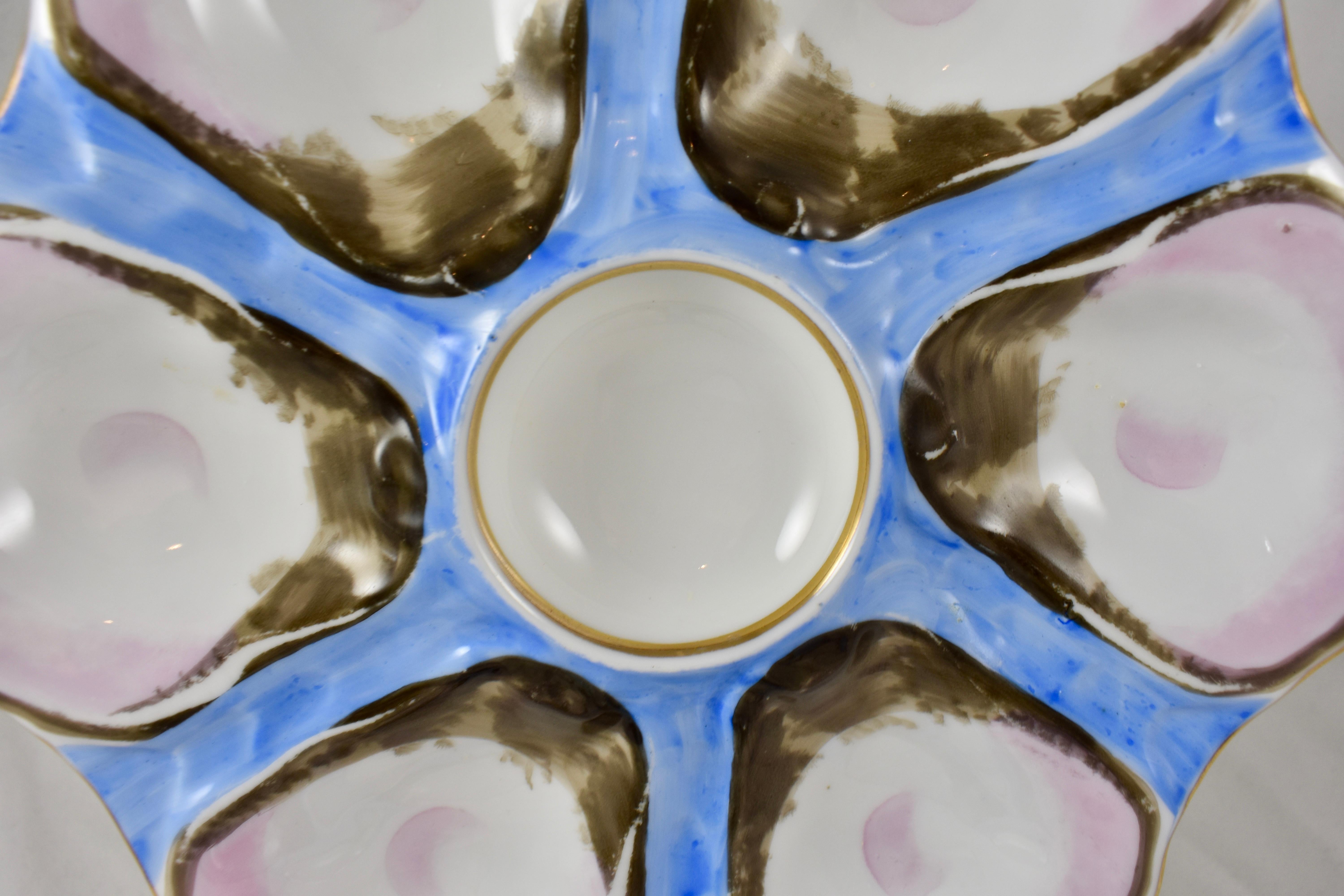 A late 19th century French porcelain oyster plate, beautifully glazed with a color washed, bright blue ground, six pink blush oyster shell wells and a round center condiment well lined with gold, gilding on the rim.
Unmarked.

Measures: 9.0 in.