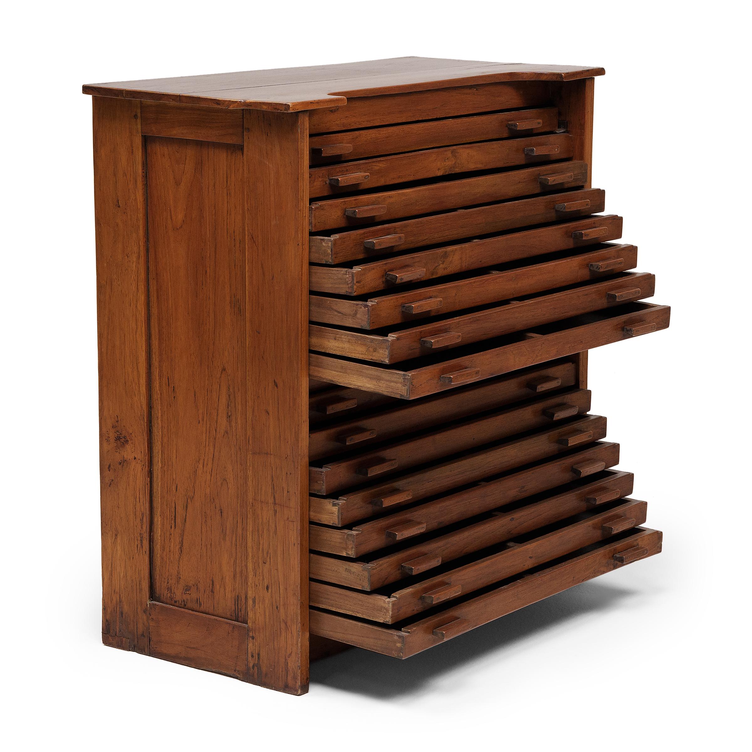 This unusual cabinet is an early 20th century flat file organizer, designed with many drawers and minimal decoration. Crafted of oak in the Arts and Crafts style, the cabinet has sixteen shallow drawers ideal for flat storage of maps, blueprints, or