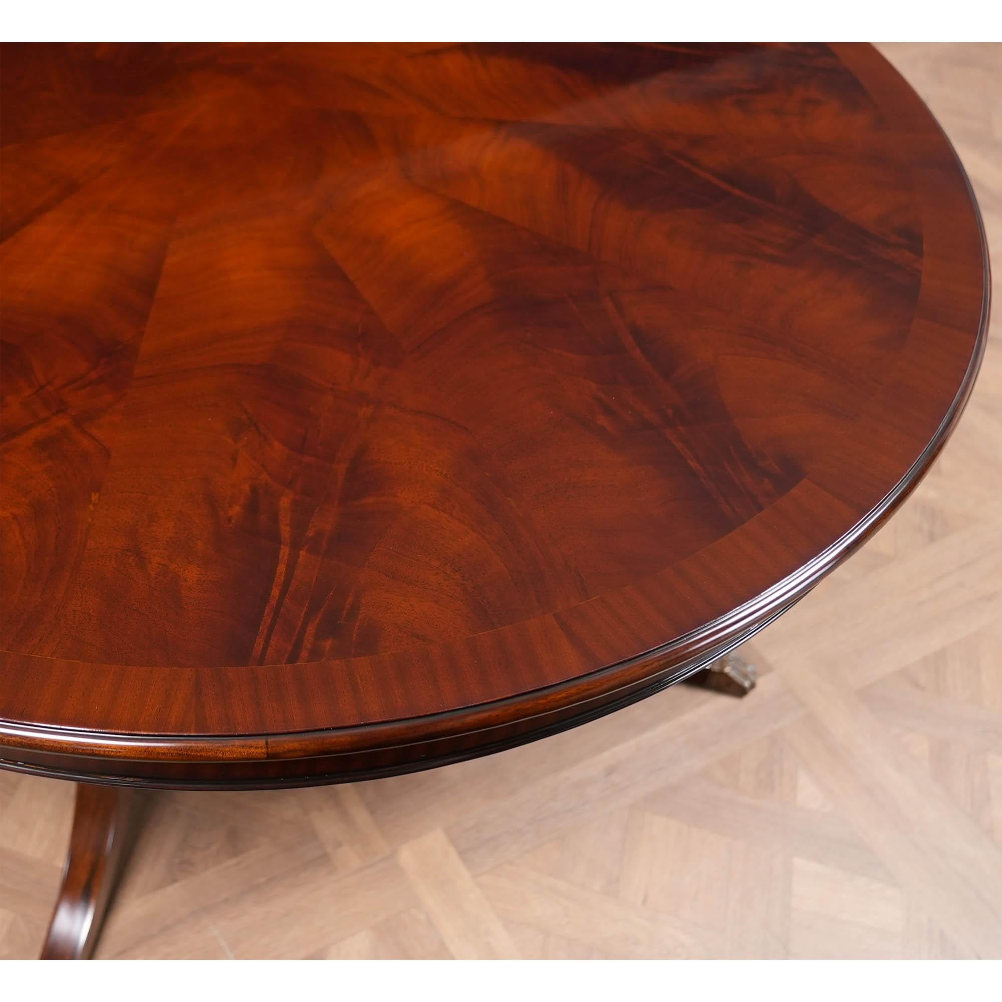 La table de salle à manger ronde en acajou de 60 pouces est fabriquée à partir d'un champ d'acajou figuré de haute qualité et d'une bande de sapelli qui crée un contraste subtil mais intéressant dans le motif du plateau.  L'élégante base de la table