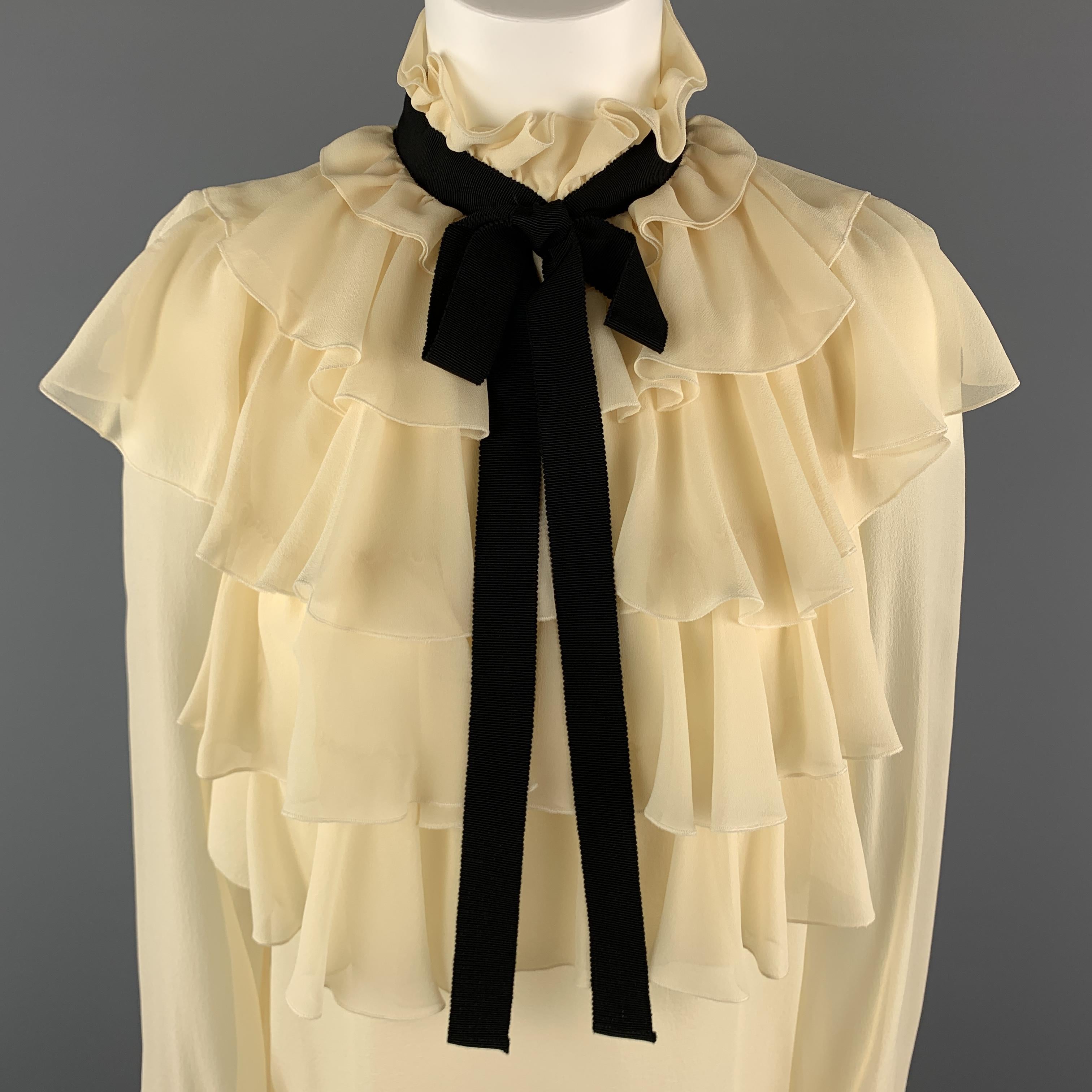 GUCCI Blouse comes in a cream tone in a silk material, with a high collar, a ruffled front and cuffs, a black ribbon, raglan long sleeves, and buttoned cuffs. Made in Italy.

Excellent Pre-Owned Condition.
Marked: IT 40

Measurements:

Shoulder: