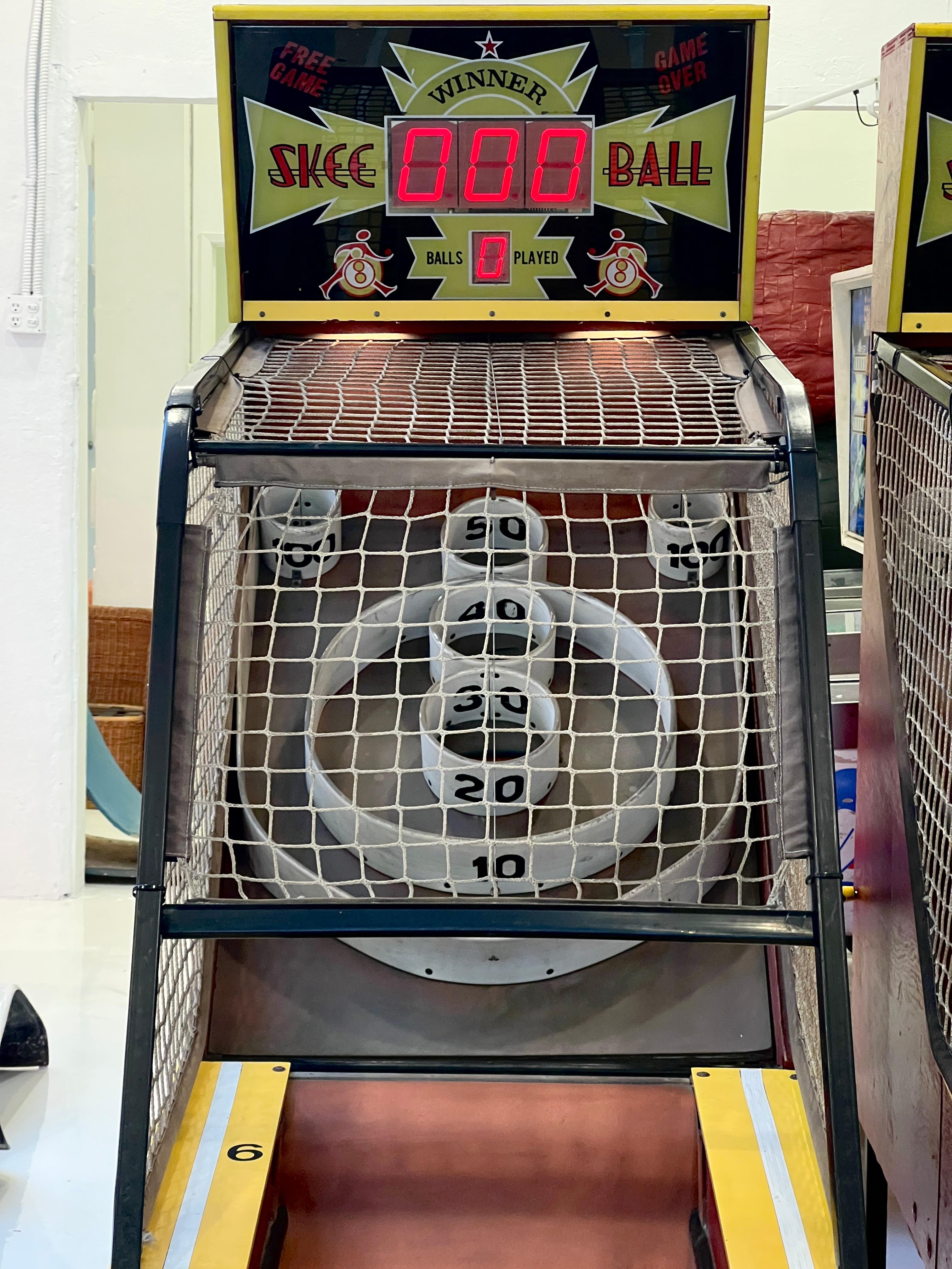 Cette machine de Skee Ball vintage est votre laissez-passer pour une nostalgie instantanée des salles d'arcade. Avec ses voies rouges emblématiques, ses guides jaune vif et ses tableaux d'affichage rétro qui s'illuminent comme une nuit de carnaval,