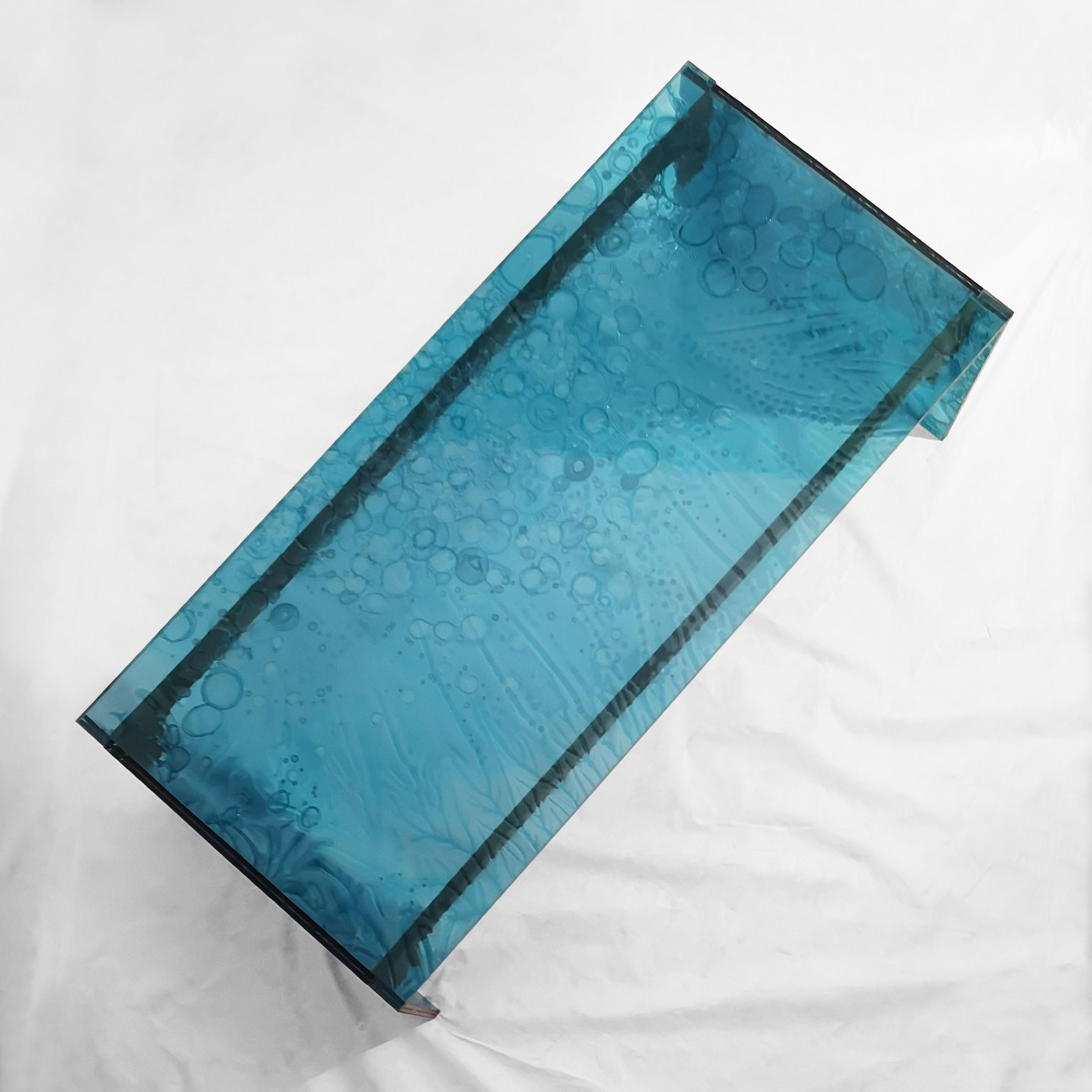 Table basse, fabriquée à la main en acrylique vert transparent coloré avec une technologie innovante.
Le matériau est fabriqué par la fusion de trois plaques, dont l'une
centre partiellement guéri.
Ce processus crée des effets uniques et