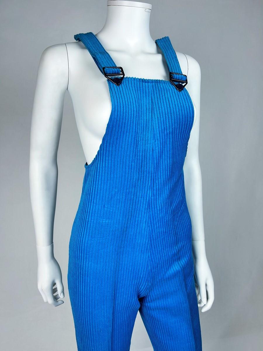 Circa 1975
Francia
Tuta da sci in velluto blu elasticizzato di Jantzen degli anni '70. Plastron stretto da cinghie con passanti in plastica nera. Taglio aderente a zampa d'elefante con pieghe ben definite e linguette di chiusura Kway blu con