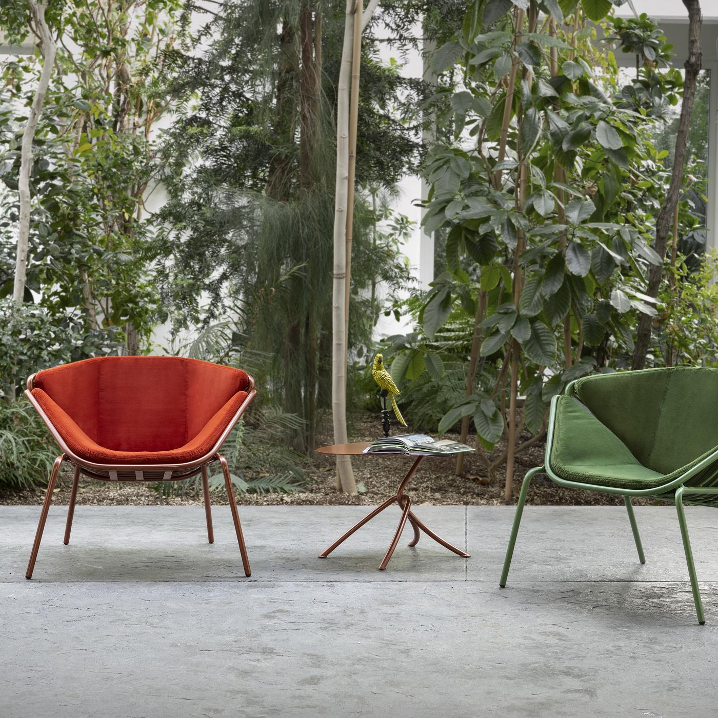 Entirely lacquered in a green hue, this striking chair has a contemporary and unique allure. It comprises a tubular metal frame with a crisscrossed design on the back and robust slanted legs, where a soft and comfortable fabric green cushion padded