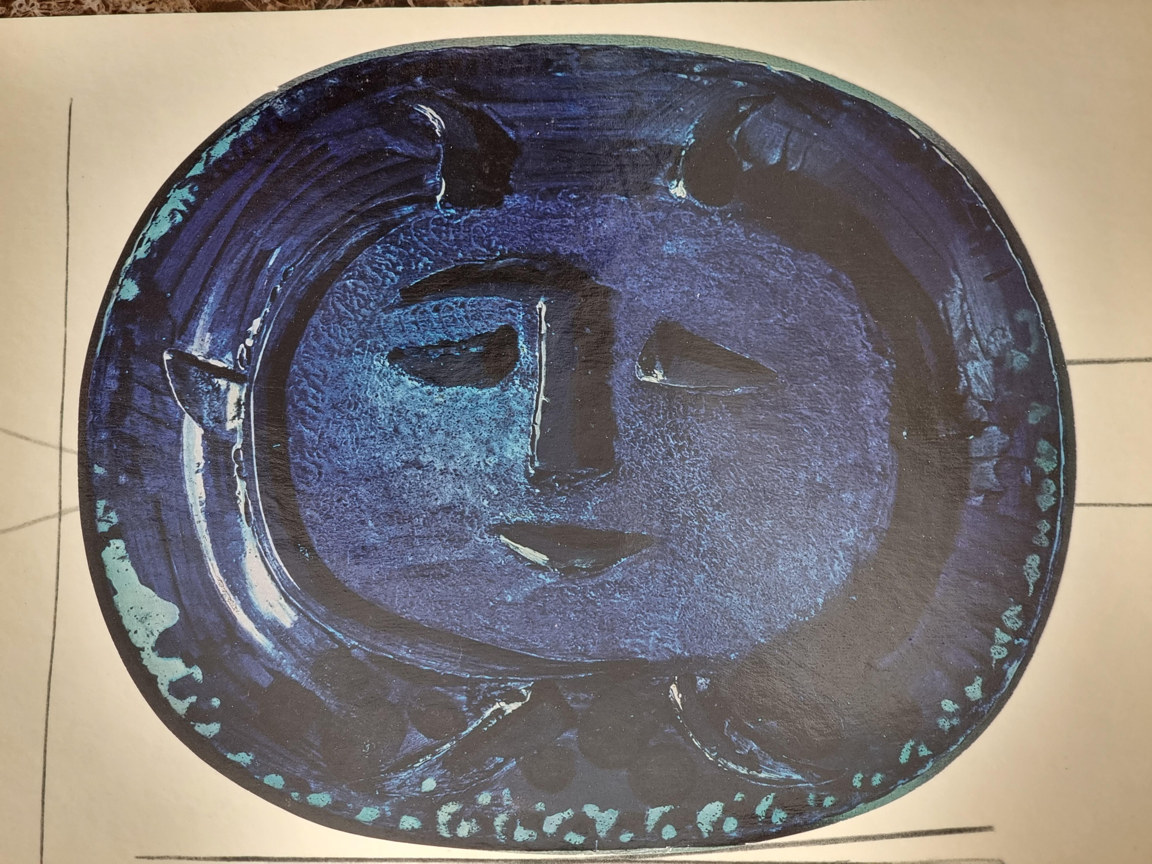 An exquisite shiny polychrome print of Picasso Vallauris ceramic plate depicting face in blue. The color print is attached to a thick, high quality paper with decorative lines. 

The print is originally from a Limited Edition Art Folio 