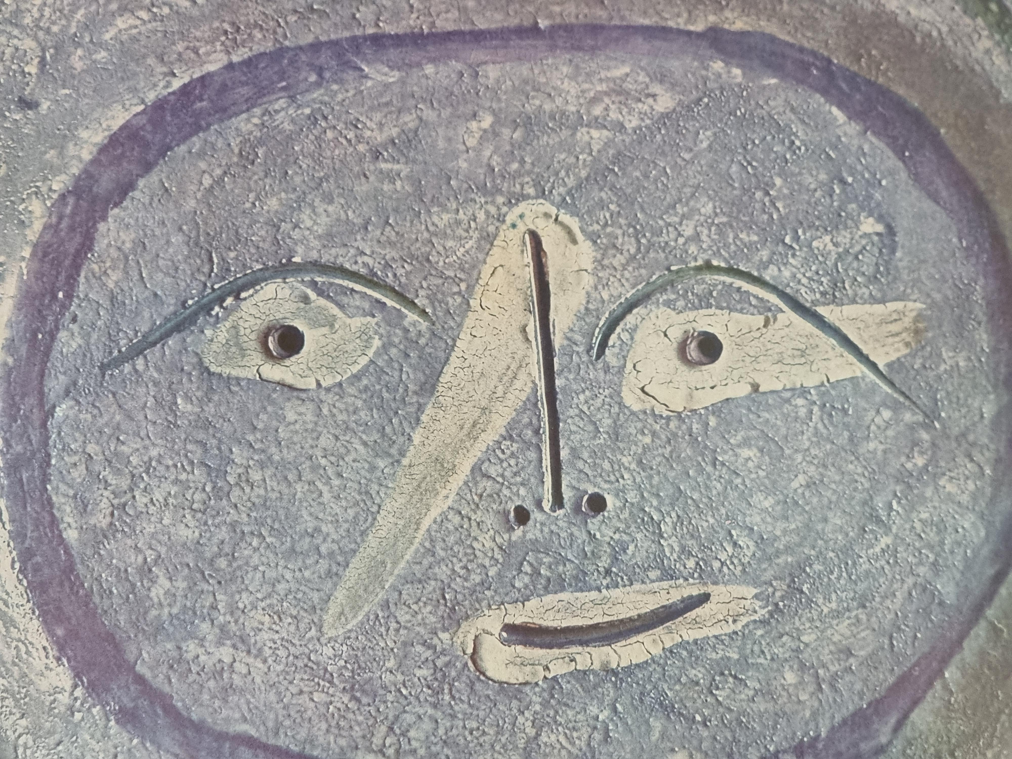 An exquisite shiny polychrome print of Picasso Vallauris ceramic plate depicting face in blue. The color print is attached to a thick, high quality paper with decorative lines. 

The print is originally from a Limited Edition Art Folio 