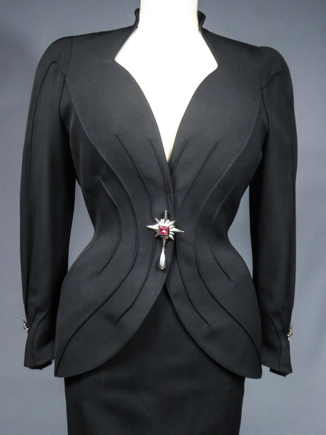 Circa 1995/1997
France

Skirt and jacket Bar set revisited by Thierry Mugler in black strecht gabardine dating from the 1990s. We naturally think of his favorite themes including the Hollywood secretary or Angel or Demon! Fitted jacket with a