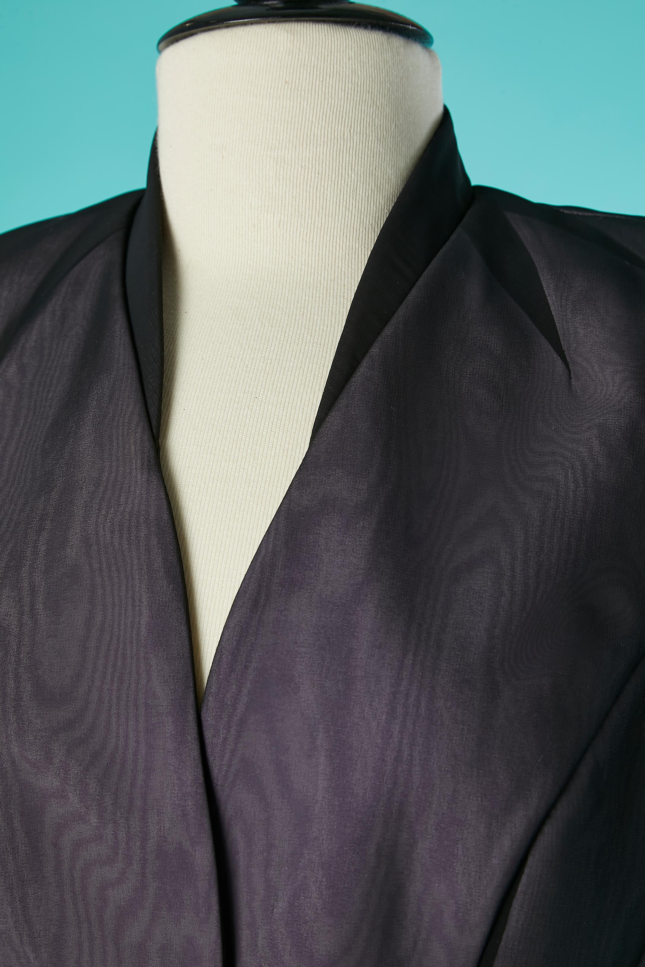 Skirt suit made of double lays of fabric and cut-work. The underlay is a lilac polyester fabric and the top lay is a black polyester chiffon. No information for the composition of the lining but probably acetate or rayon. Cut-work around the