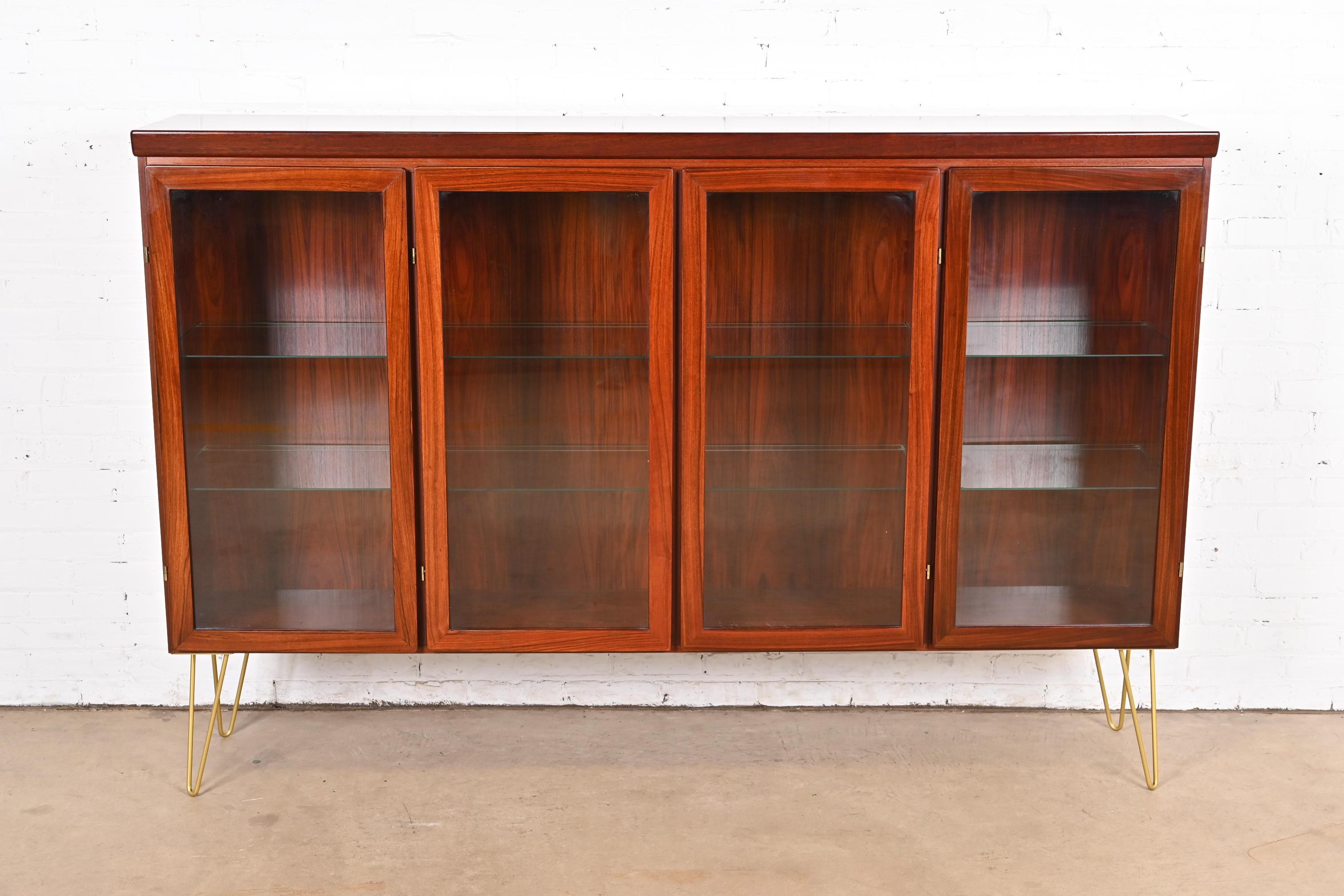 A sleek and stylish mid-century Danish Modern lighted bookcase or display cabinet

By Skovby Møbelfabrik

Denmark, Circa 1970s

Rosewood, with glass front doors, glass shelves, and brass-finished steel hairpin legs.

Measures: 77.5