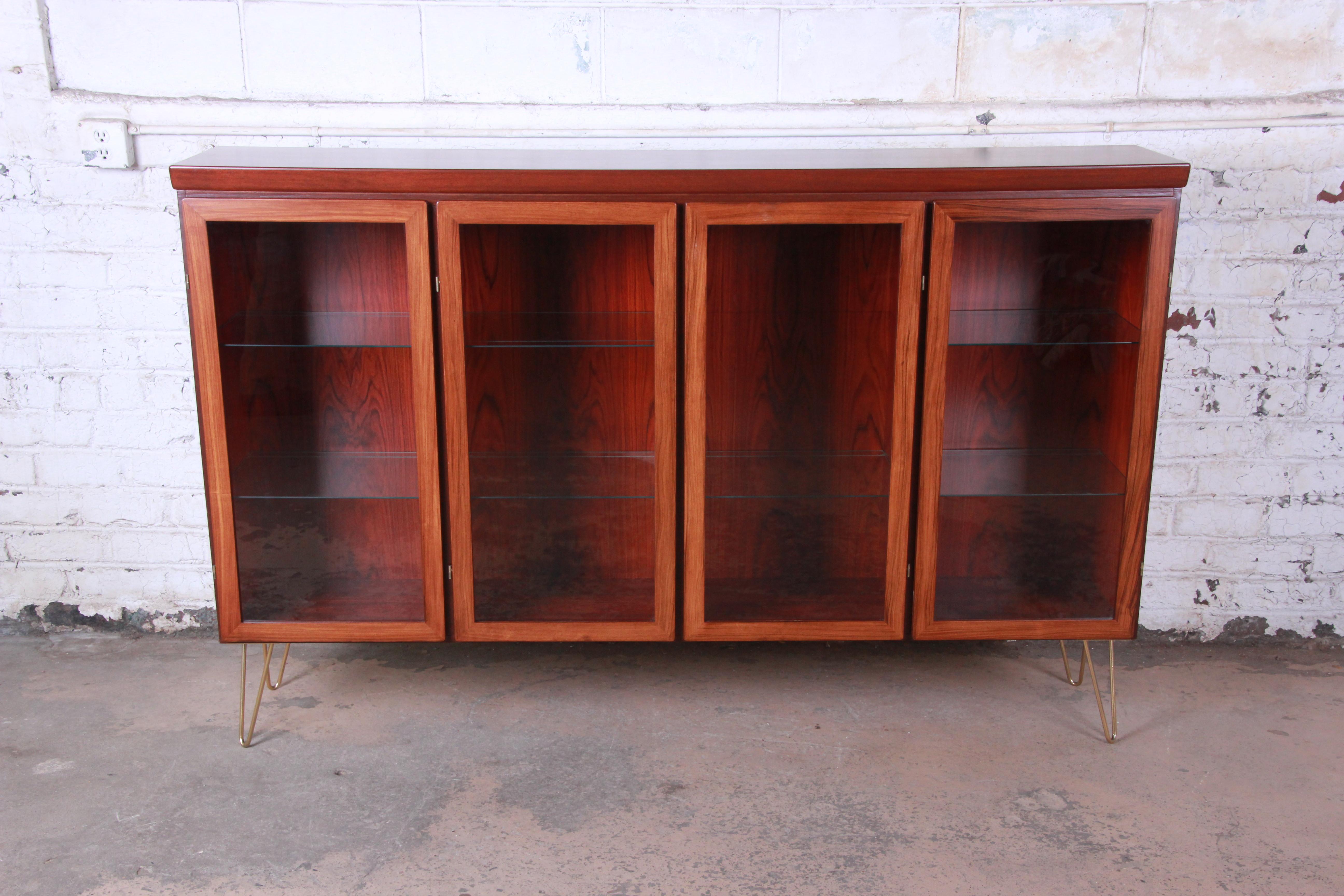 Offering an exceptional Danish rosewood glass front bookcase on hairpin legs by Skovby. The bookcase has four glass front doors that open up to adjustable glass shelves. The rosewood case is newly refinished with beautiful wood grain. The piece