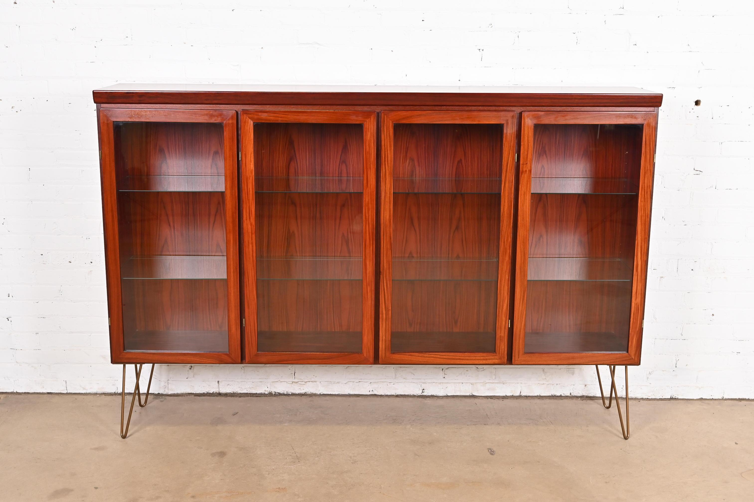 A sleek and stylish mid-century Danish Modern lighted bookcase or display cabinet

By Skovby Møbelfabrik

Denmark, Circa 1970s

Rosewood, with glass front doors, glass shelves, and bronze-finished steel hairpin legs.

Measures: 77.5