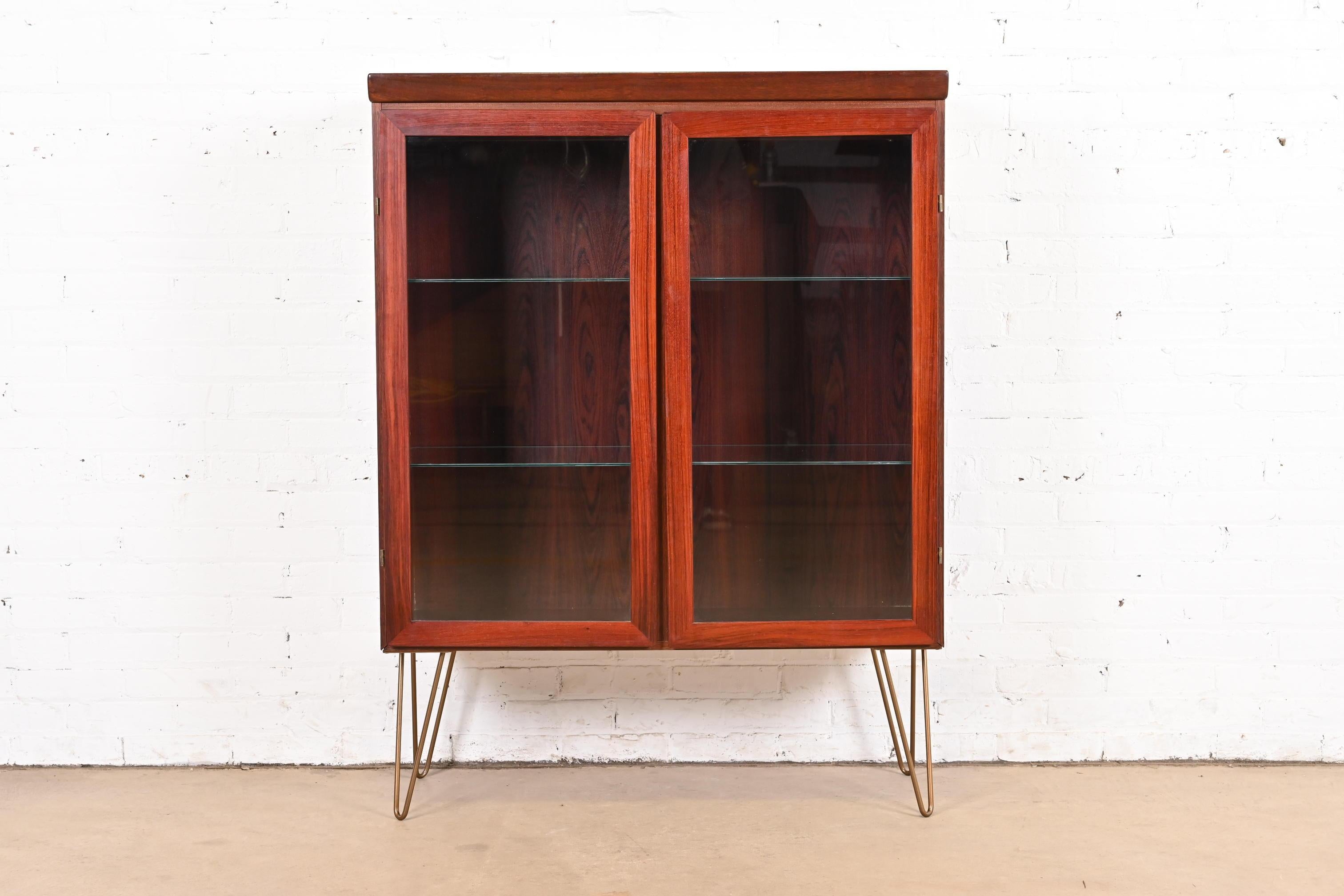 Una libreria o vetrinetta illuminata elegante e moderna danese di metà secolo

Da Skovby Møbelfabrik

Danimarca, circa anni '70

Palissandro, con ante frontali in vetro, ripiani in vetro e gambe a forcina in acciaio con finitura bronzo.

Misure: 39