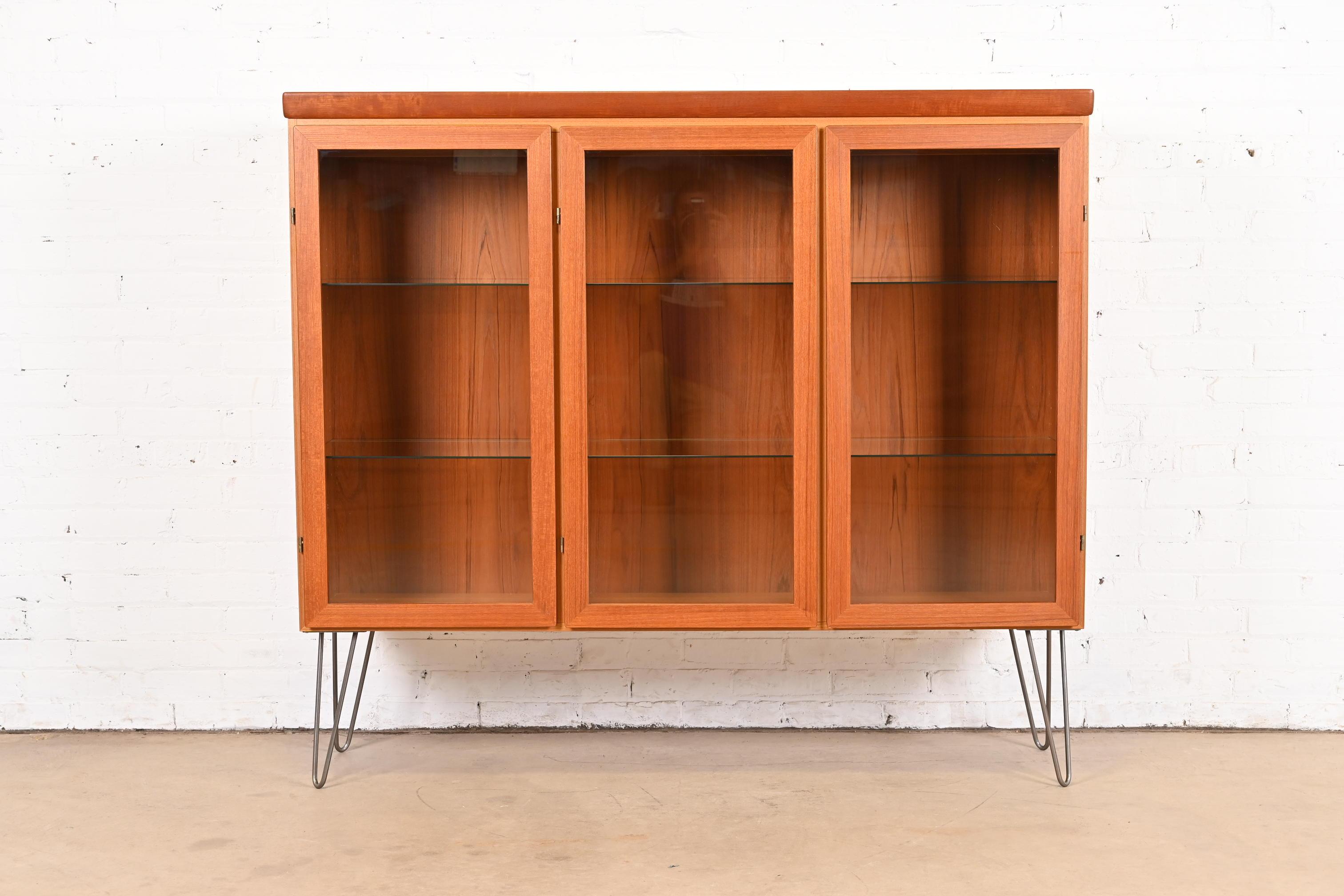 A sleek mid-century Danish Modern triple bookcase cabinet

By Skovby Møbelfabrik

Denmark, Circa 1970s

Teak, with glass front doors and interior shelves and steel hairpin legs. Interior lights are tested and working.

Measures: 58.25