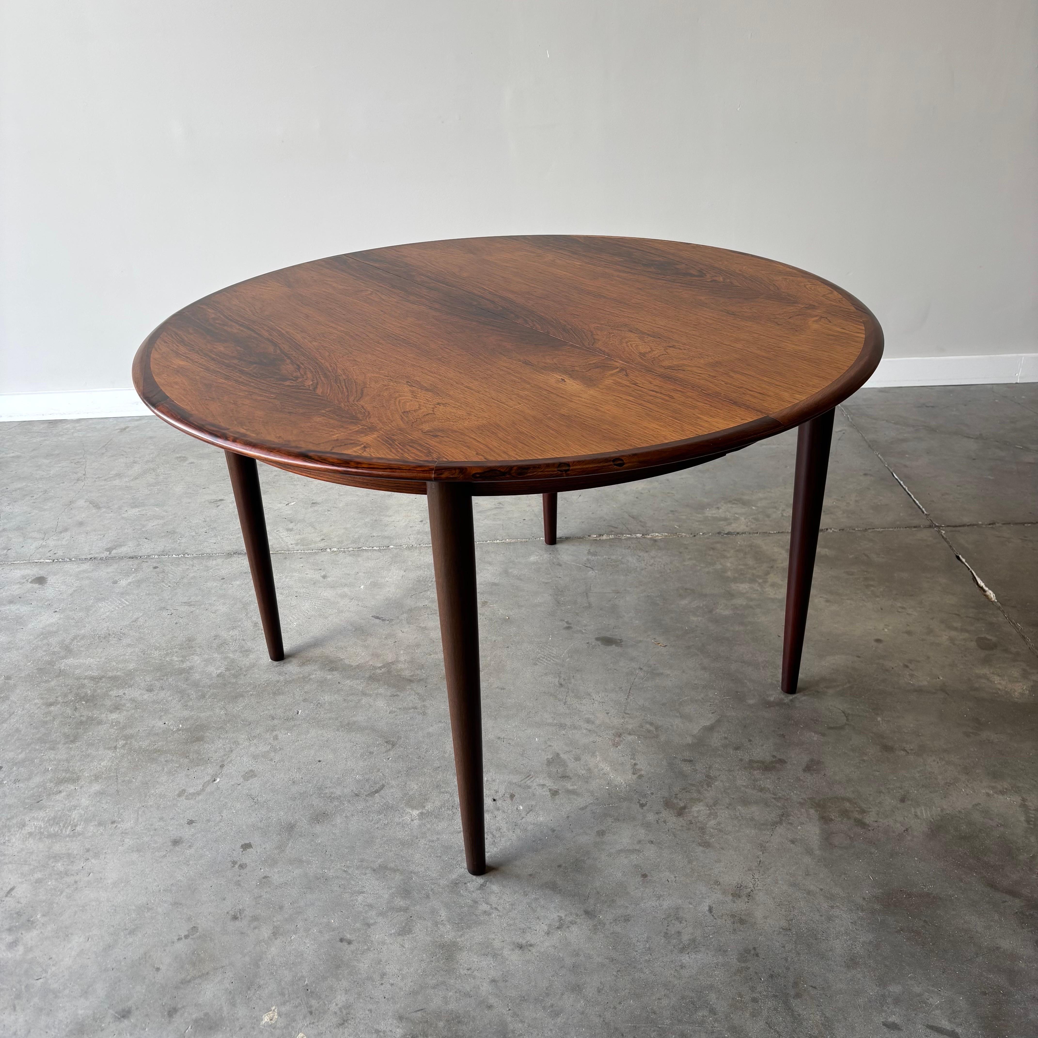 Questo splendido tavolo da pranzo in legno di palissandro, realizzato dagli stimati produttori danesi Skovmand & Andersen, esemplifica l'eleganza e la funzionalità del design moderno danese degli anni '60. Il tavolo ha un generoso diametro di 48