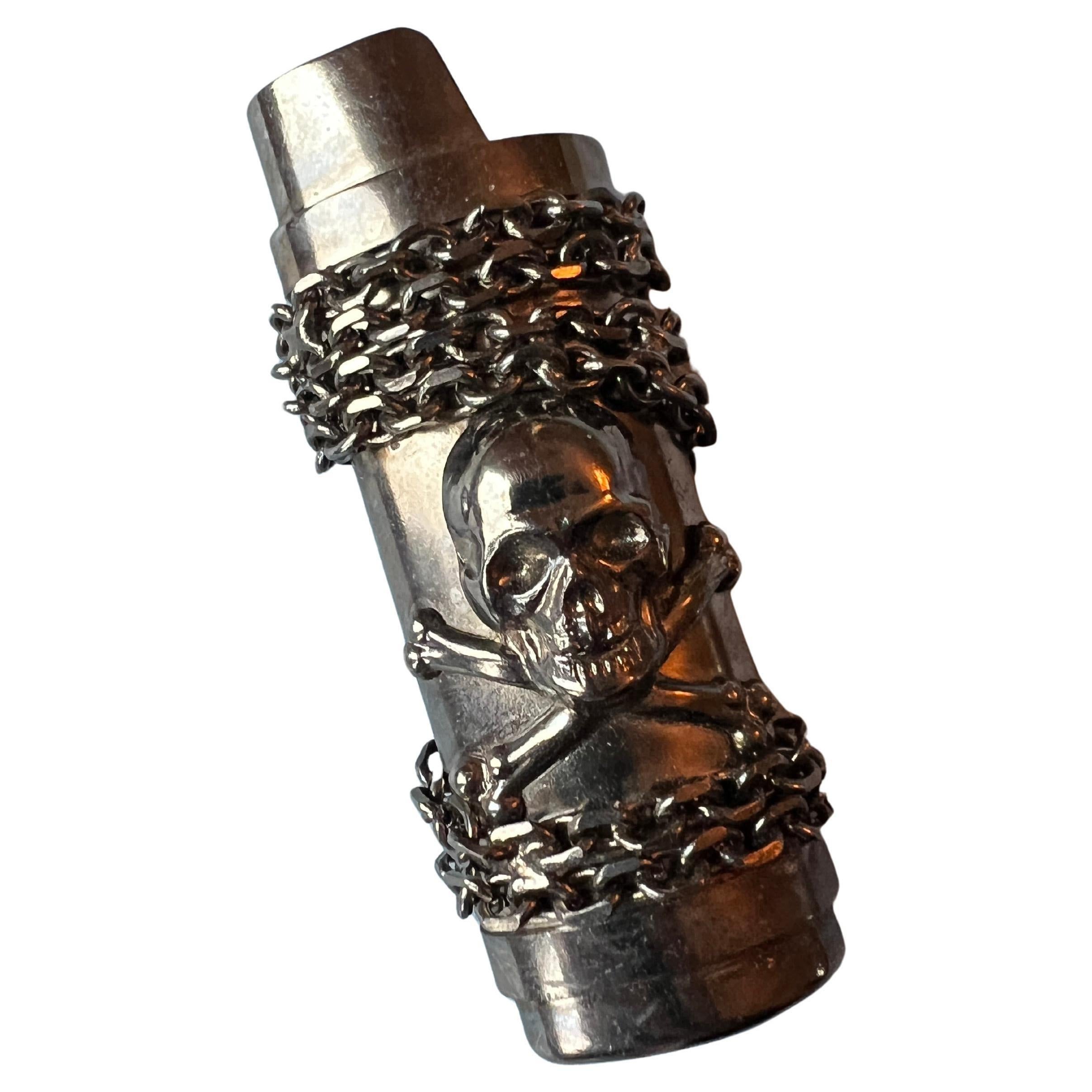 Skull and Bone, Light  Holder with Chains in a Ruthenium Plating, Vintage 2008.

Measurement: 
Height 3 1/4 inches, width 1 1/16 inches

Condition: Has lost a bit of shine and features minor markings indicative of its age and history, enhancing its