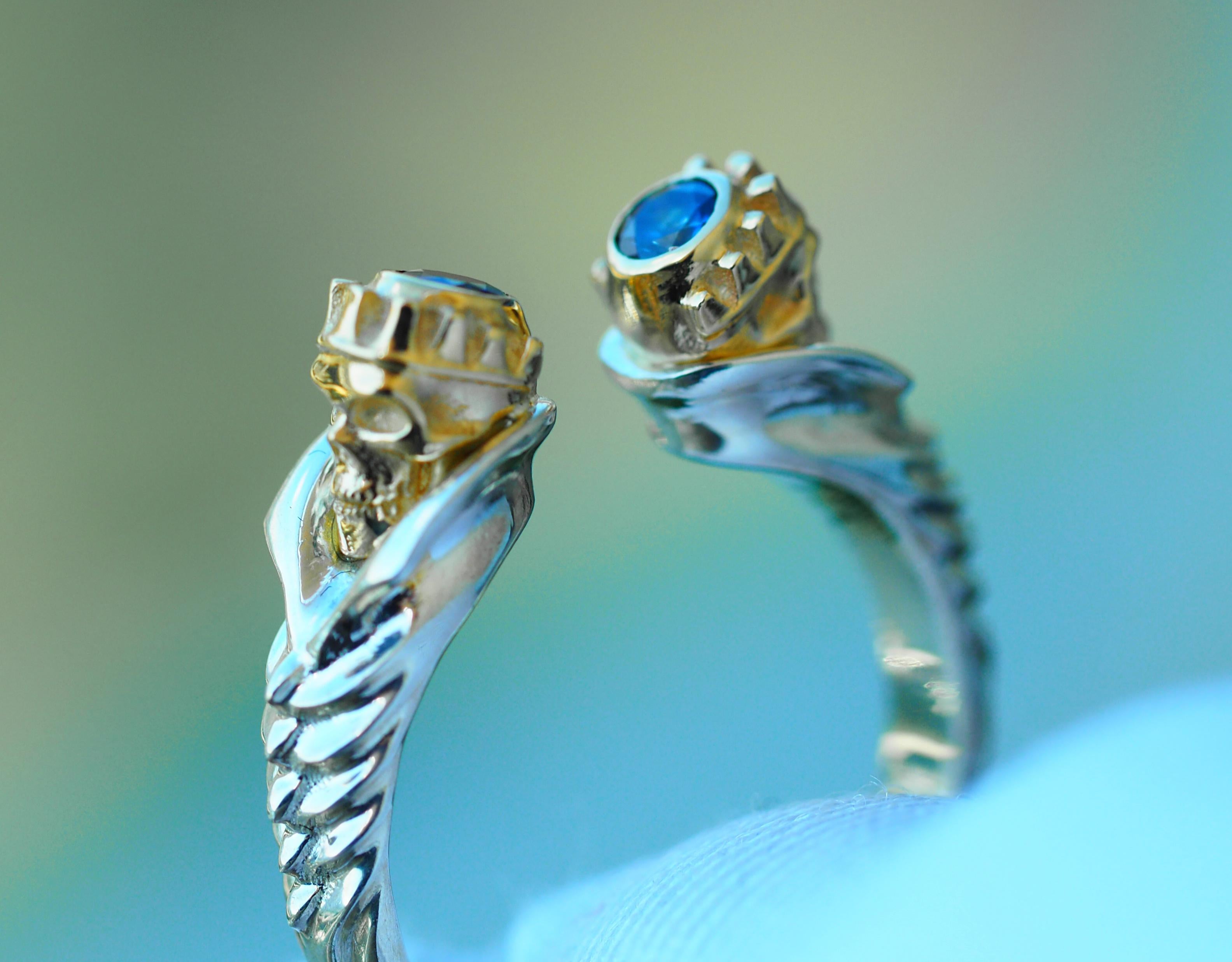 Totenkopfring mit blauen Saphiren. 
Skull-Ring aus 14k Gold. Halloween Ring Geschenk. Ring mit blauem Saphir. Skelett-Ring. Offener Totenkopfring. Gotischer Ring.

Metall: 14k Massivgold.
Farbe: weiß und gelb.
Gewicht - 4,5 g (abhängig von der