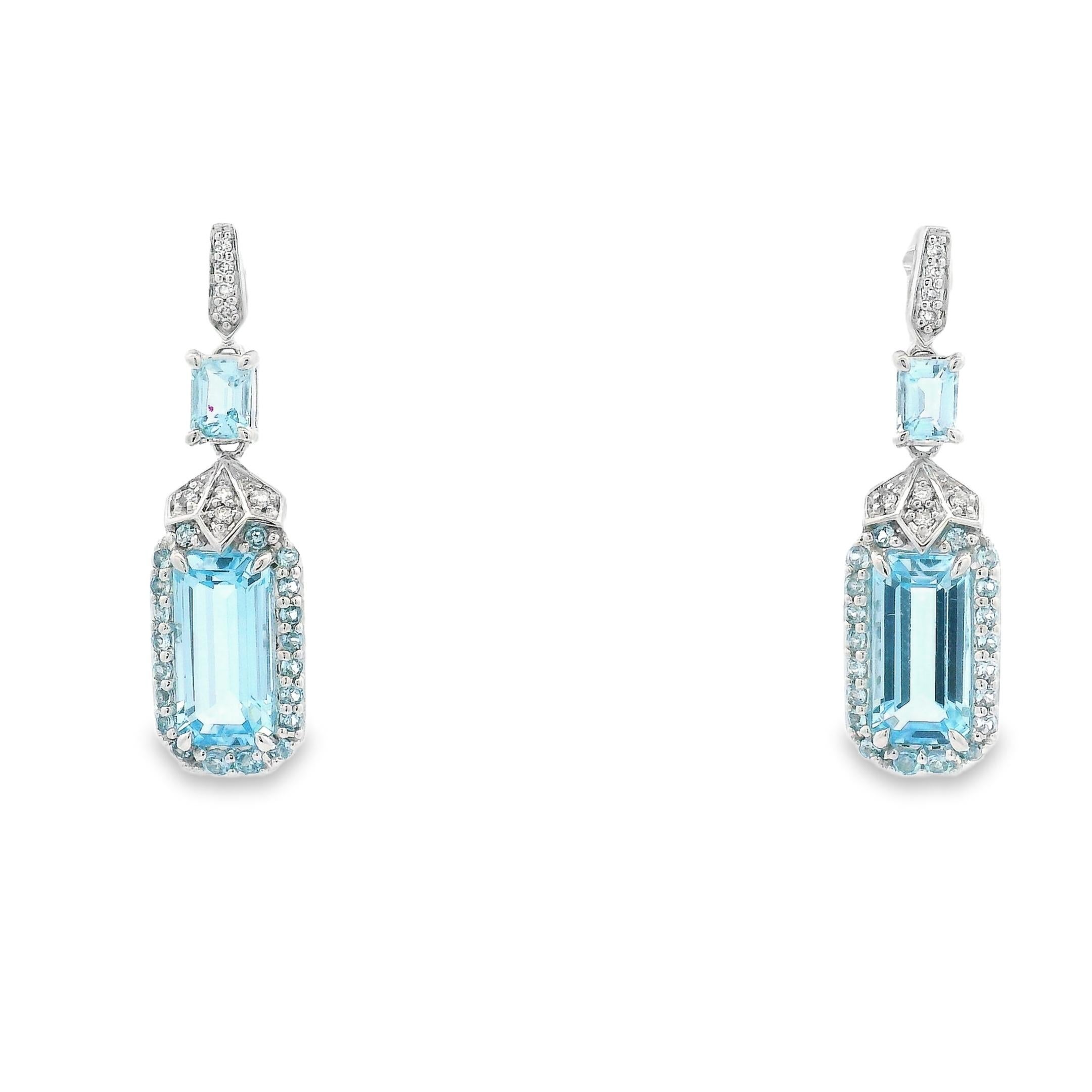 These elegant drop earrings feature faceted octagon-cut sky blue topaz stones framed by a halo of round sky blue topaz, adding layered depth and tonal brilliance. Above the halo, a smaller step-cut topaz connects the drop to a diamond-accented post,