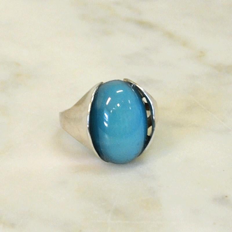 A beautiful ring from circa 1950s-1960s. Modernism. The ring has a beautiful heaven blue stone fitted into a base of silver.
Inner diameter is 1.9 cm, length of stone 1.7 cm, width of stone 1.3 cm. Weight 8.0 gram. Condition as in the pictures is