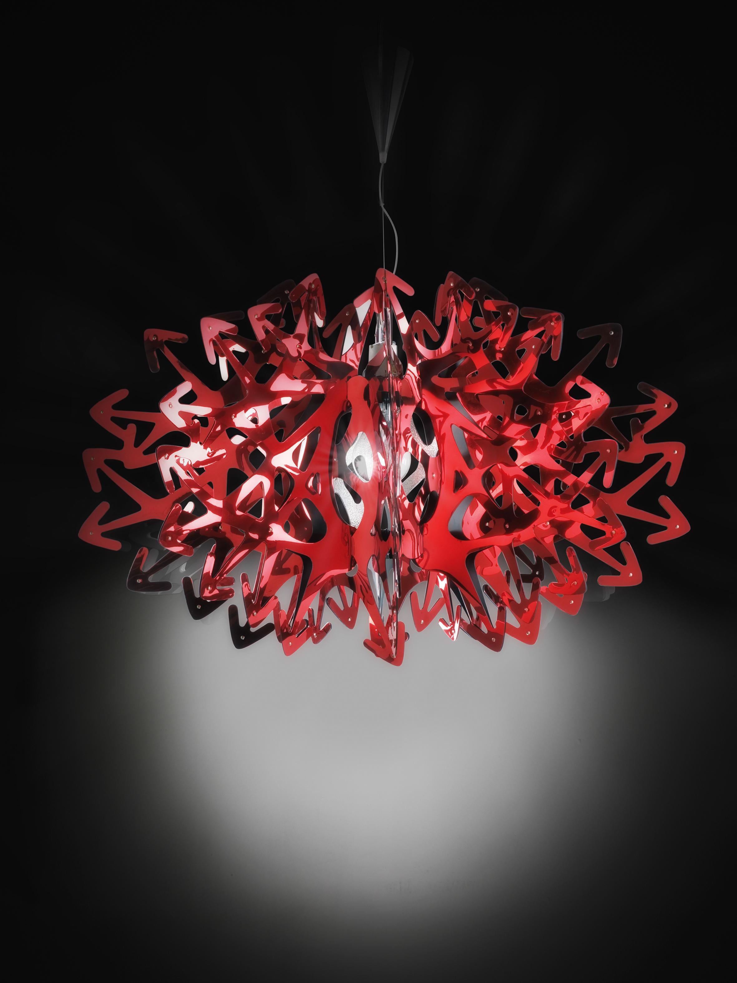 A meter-wide, opulent chandelier that brings sparkle to any interior. The layering of multiple, red metalized Steelflex® arrows make Devil mysterious and seductive, a tempting choice for spaces in need of personality and charisma. The lamp casts a
