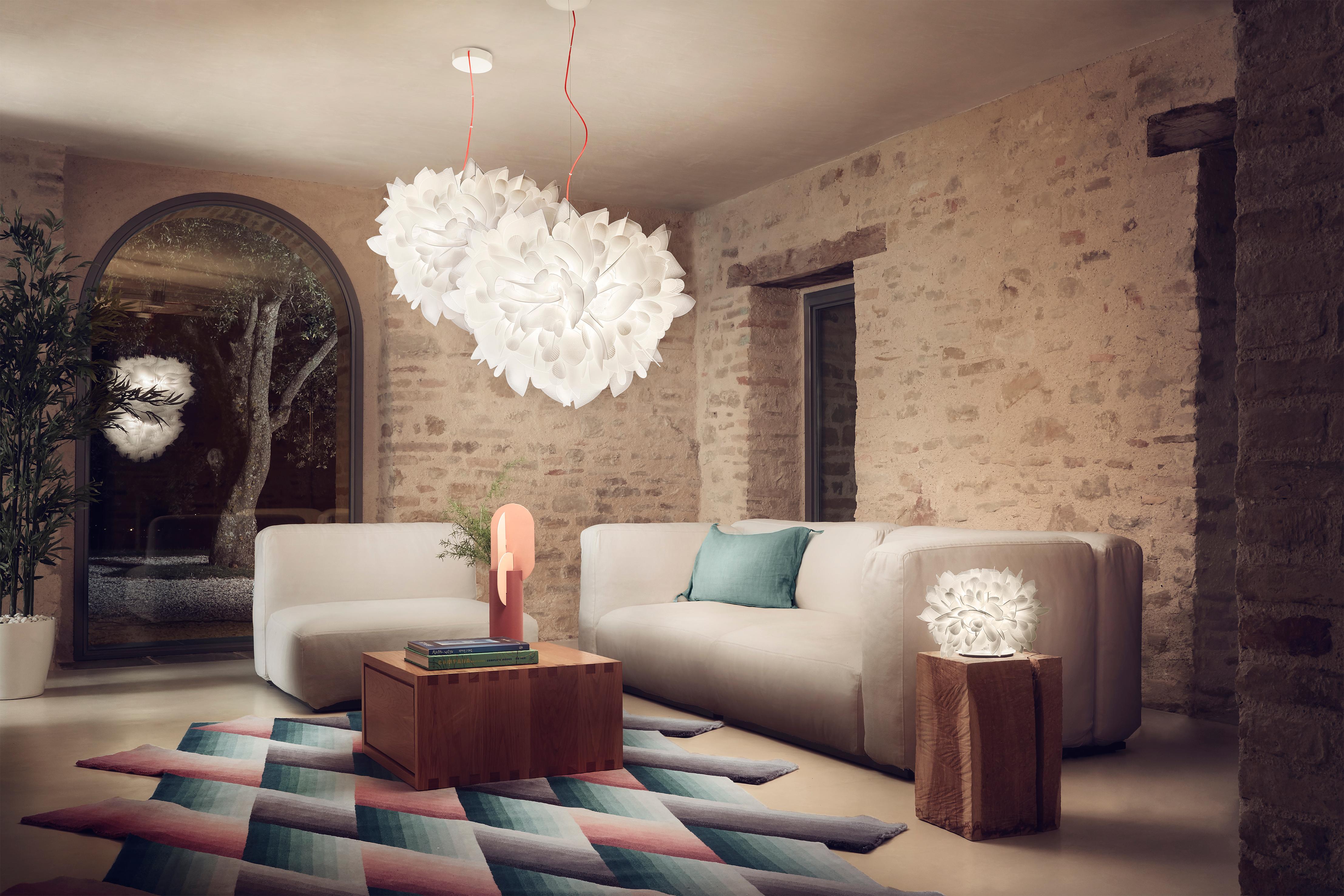 Un acabado suave inspirado en las texturas de los tejidos modernos. Veli Couture llena y envuelve cualquier espacio, distinguiéndolo por su estética y sus exuberantes características decorativas. El cable rojo enrollado de la suspensión aumenta la