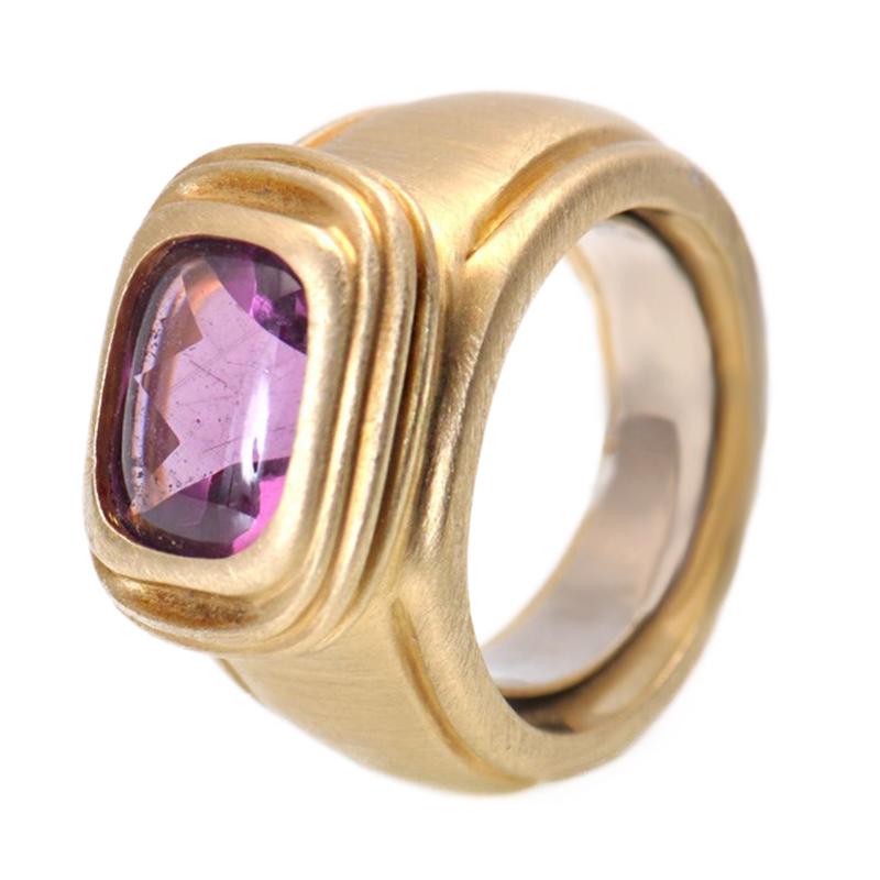 Slane & Slane 18K yellow gold medium rectangular ring encompassing all the iconic design elements from these two talented sisters - brushed matte yellow gold forms a wide band . 
The setting is slightly raised and features a smooth amethyst stone