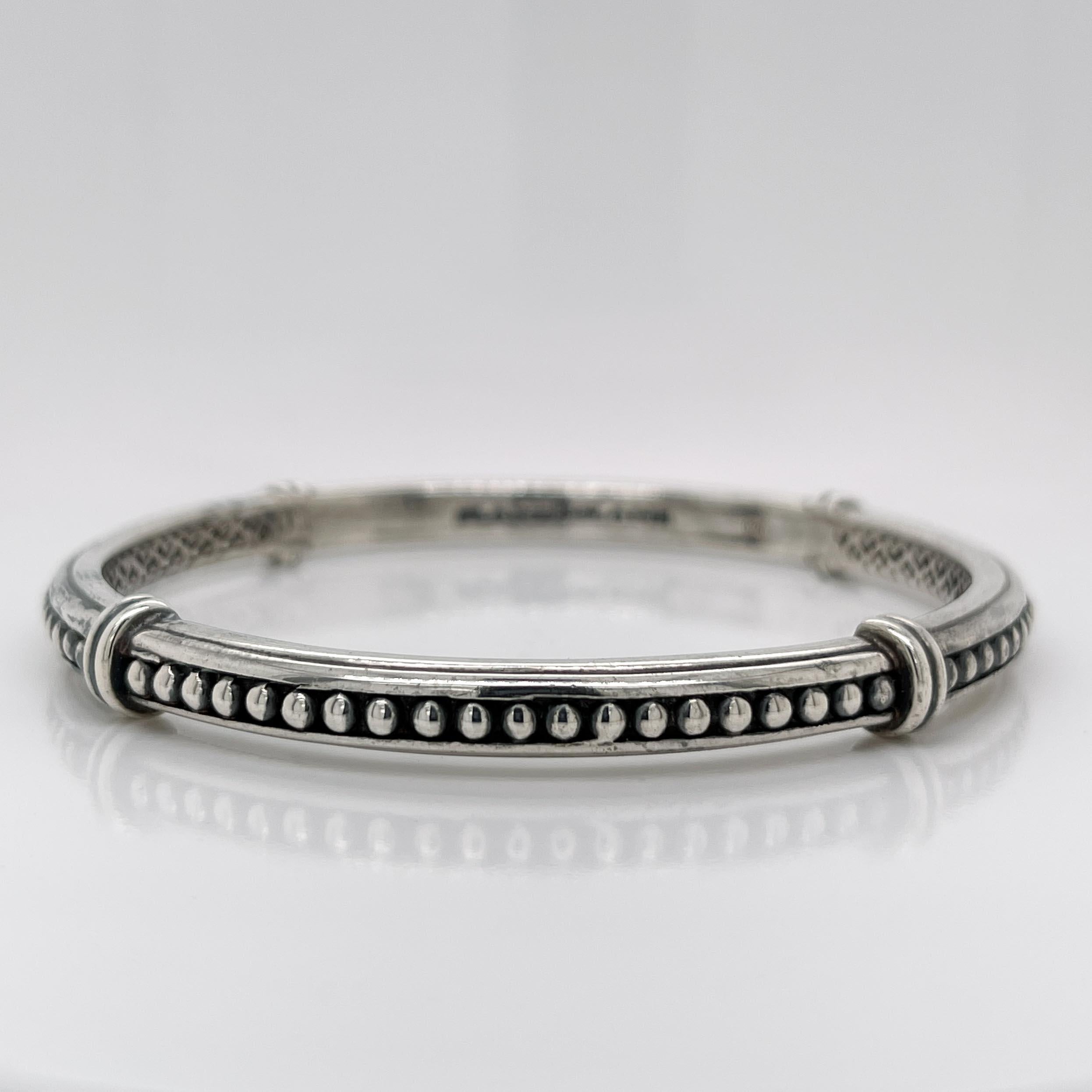 A fine Slane & Slane sterling silver bangle bracelet.

In sterling silver.

By Slane & Slane.

With a silver beaded column channel set between ribbed design and an interior with open work, connecting hearts, and a deeply engraved SLANE & SLANE mark.
