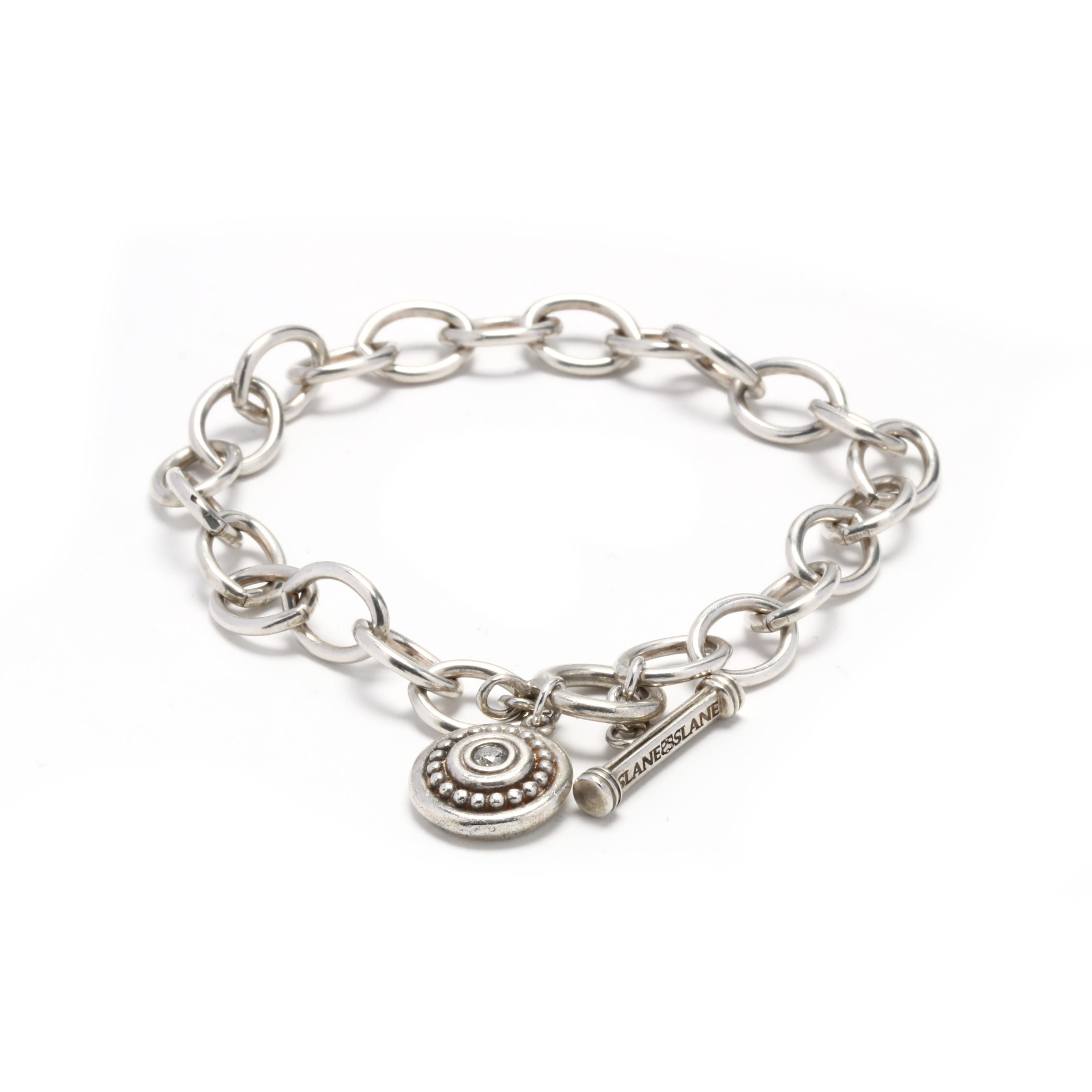 A sterling silver diamond bead charm bracelet design by Slane and Slane. This bracelet features an oval link toggle bracelet with a round beaded charm with a bezel set diamond accent.



Stones:

- diamond, 1 stone

- full cut round

- 2.75 mm

-