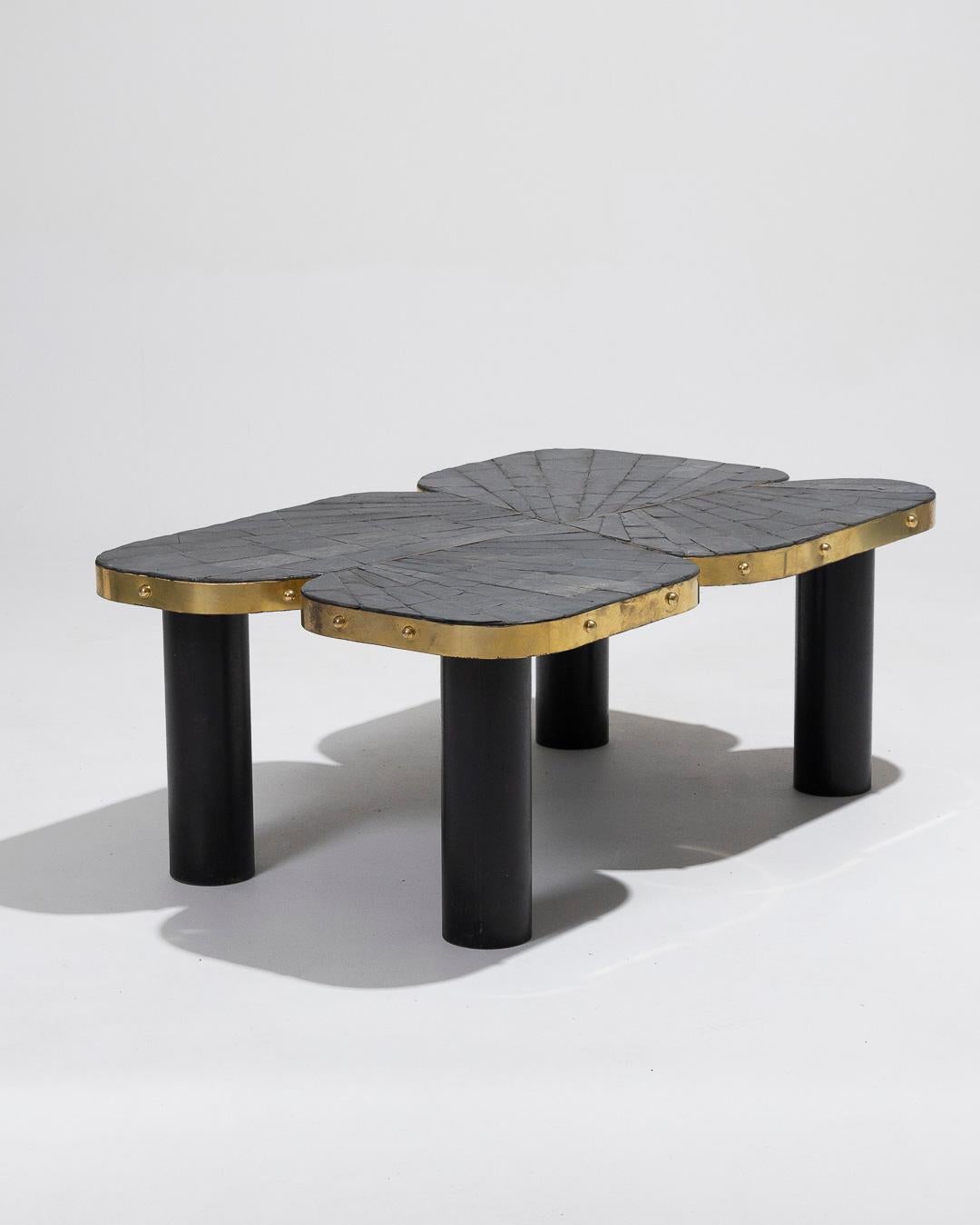 Table basse en marqueterie d'ardoise et de laiton. Pièce unique, réalisée par l'artiste français d'origine serbe Marko. De forme irrégulière et organique, le plateau est serti d'ardoise et entouré d'une large bande de laiton. Les quatre pieds