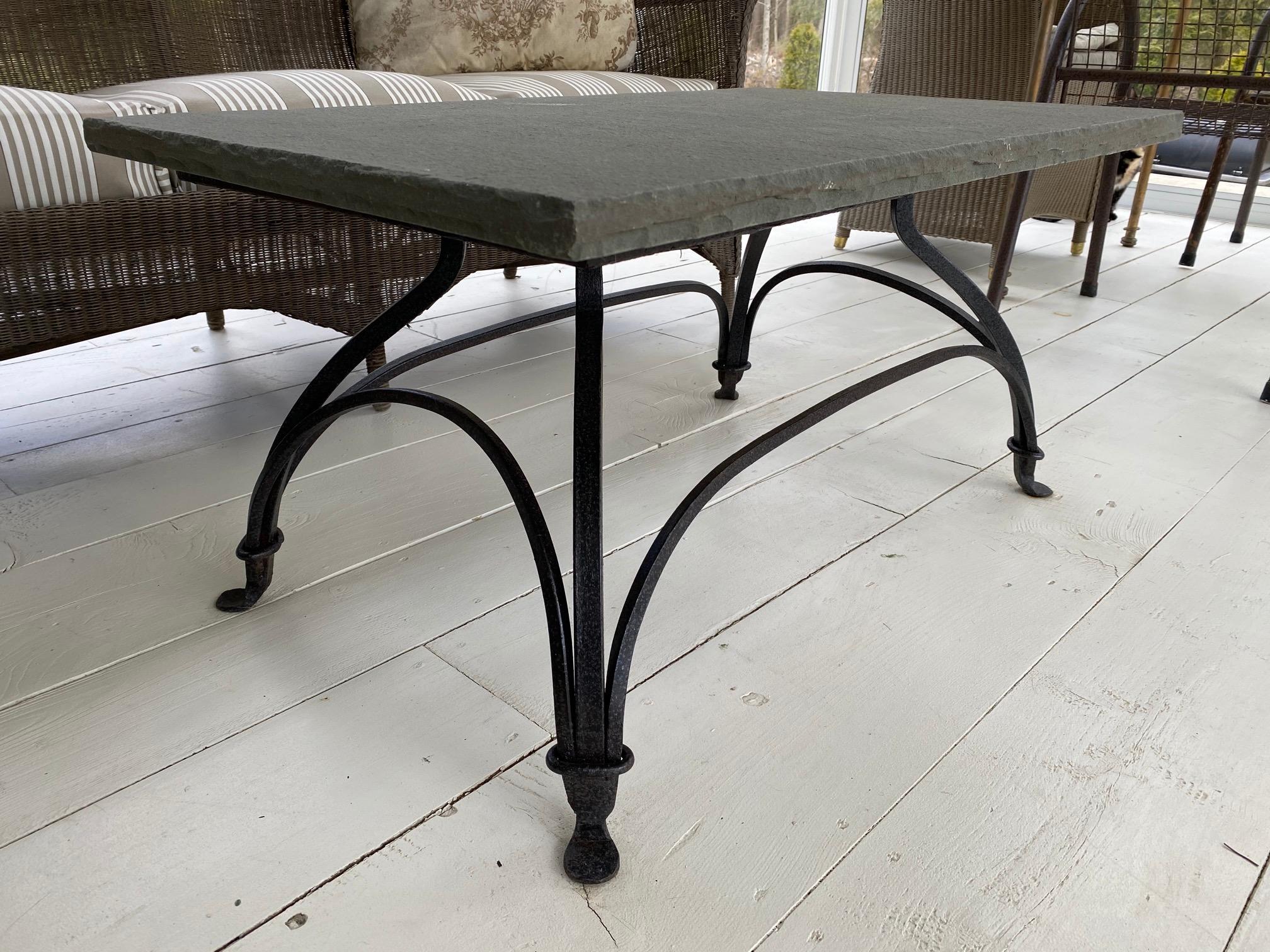 Indoor or outdoor metal base garden coffee table with slate top married to a bronze colored wrought iron base that is secured by gracefully arched stretchers and ended at the bottom by padded feet. Top and base can be sold separately. Top: 900/base: