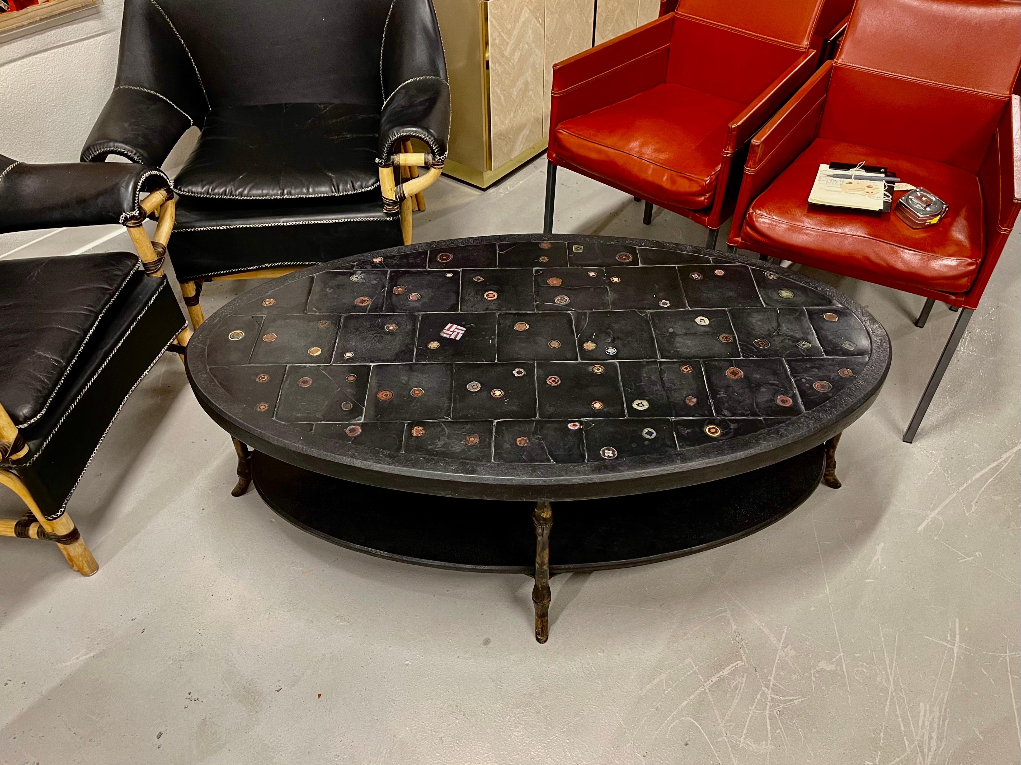 A beautiful slate table with millefiore art glass inlaid pieces. Likely from Ironies. Purchased in the 1990’s. Great oval shape. Two tiers, the slate pieces are removable for transport. Faux bamboo legs with a touch of gilt. The top of the table has
