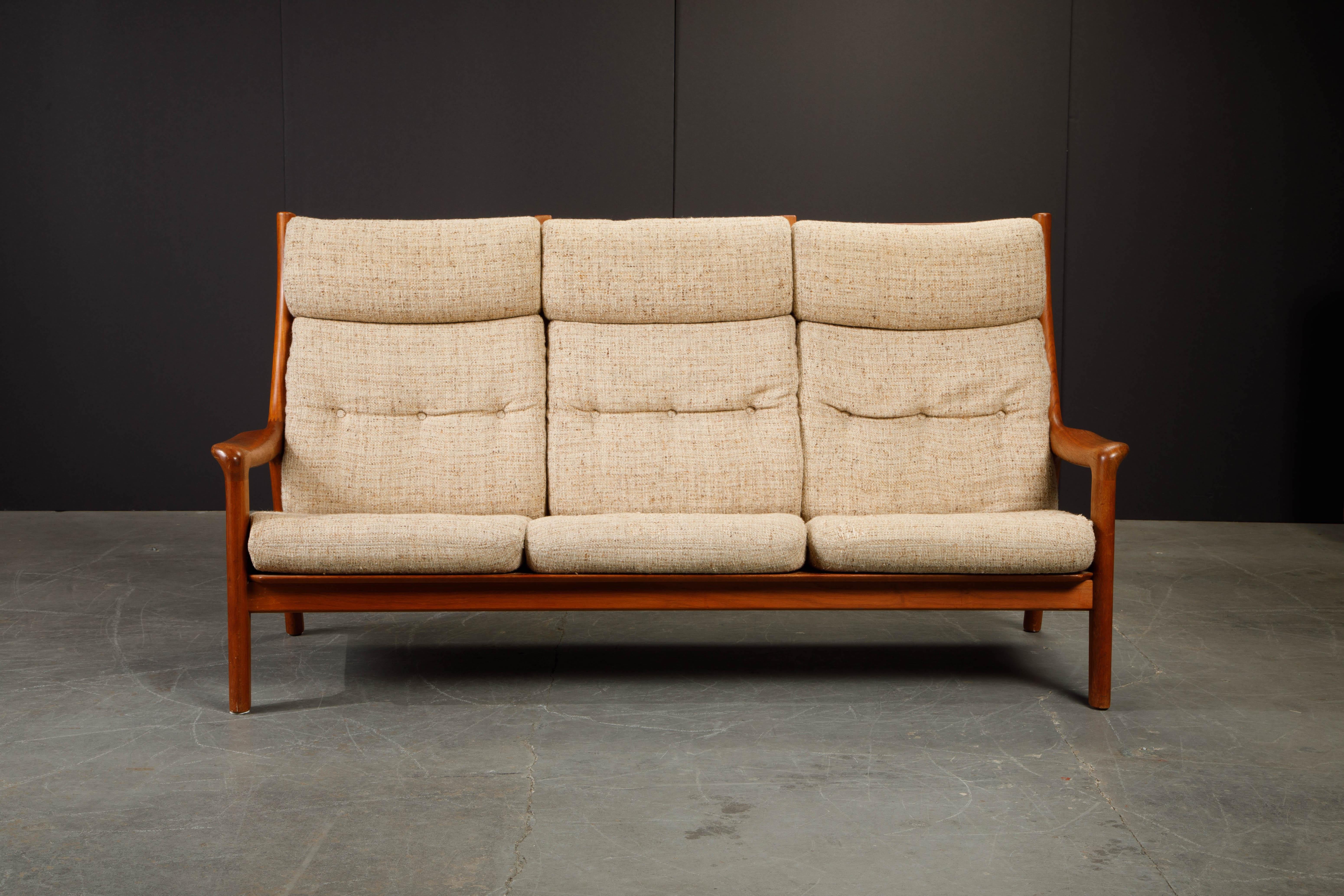 This Danish Mid-Century Modern sofa was made in the 1970's in Denmark. Featuring thick sculpted arms with a solid teak frame and slatted back, with tufted cushions upholstered in its original fabric, making this sofa just as comfortable as it is