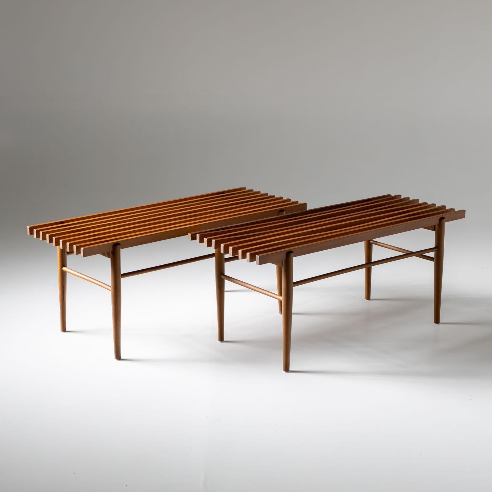 Pair of benches on conical legs with smooth connecting struts and seats made of square slats.