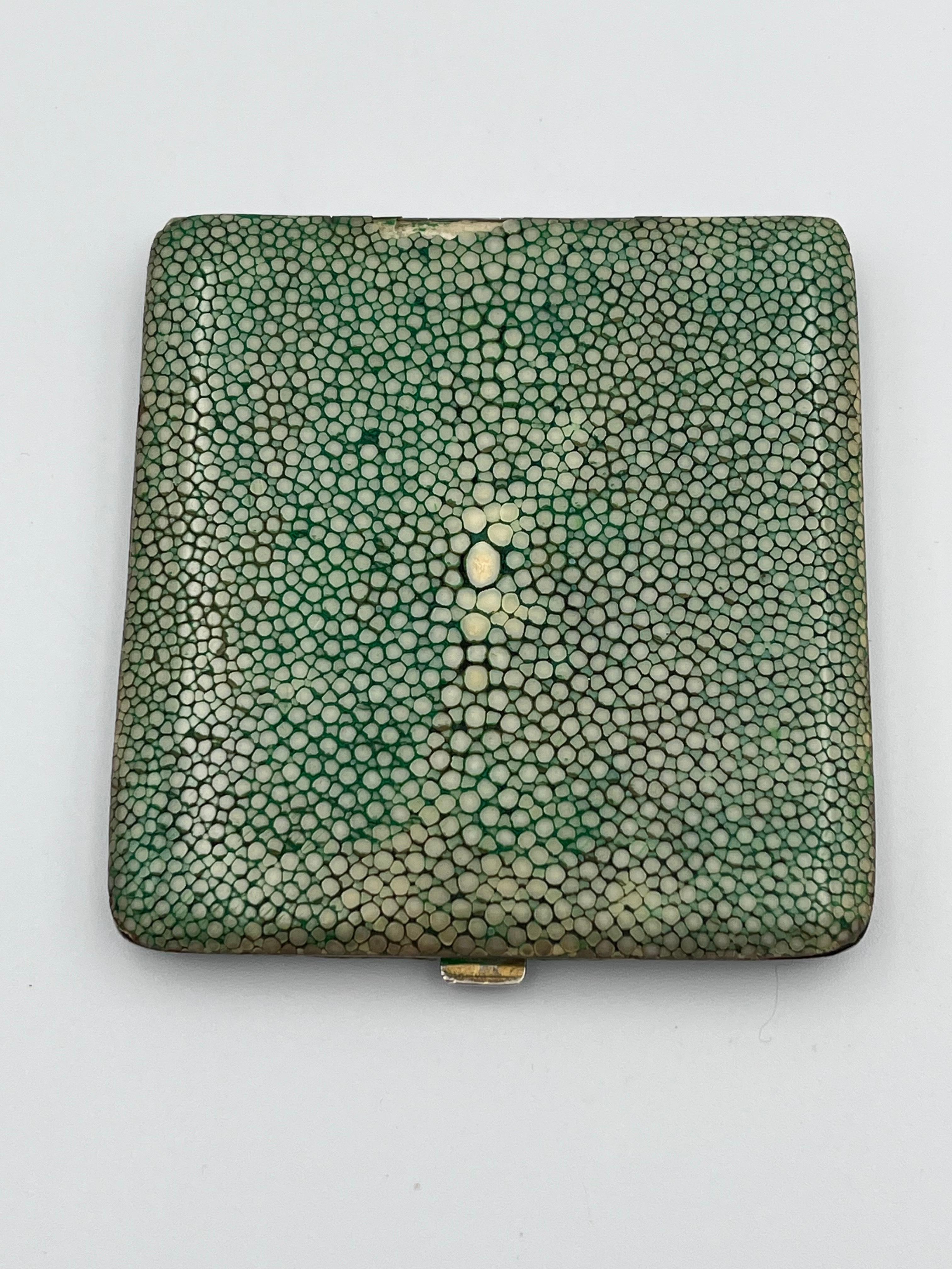 Elegante portasigarette Art Deco anni '30 in zigrino con interno dorato

Questo elegante portasigarette in zigrino Art Déco incarna la sobria eleganza e la raffinatezza del design di lusso degli anni Trenta. Con la sua silhouette sottile e