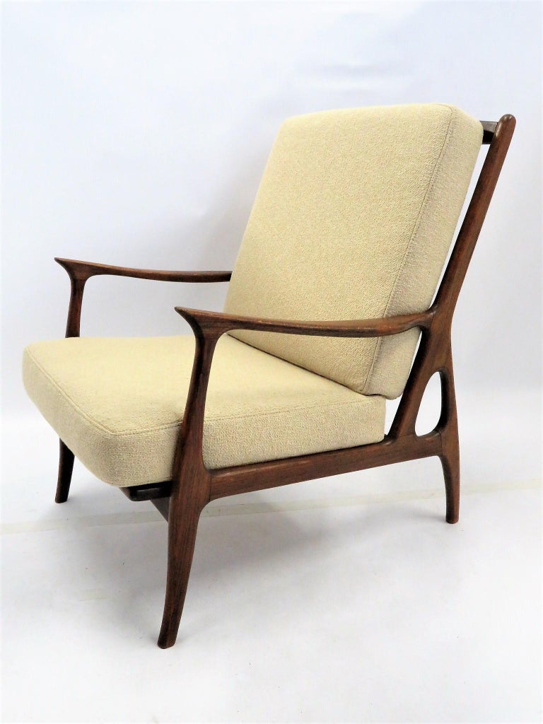 Made in Italy, this sculpted hardwood armchair has a Danish Modern style with shaped arms and legs and an amoeba opening in front of the back leg. One immediately thinks of Borsani designs. Featuring new cushion upholstery in a dark cream colored