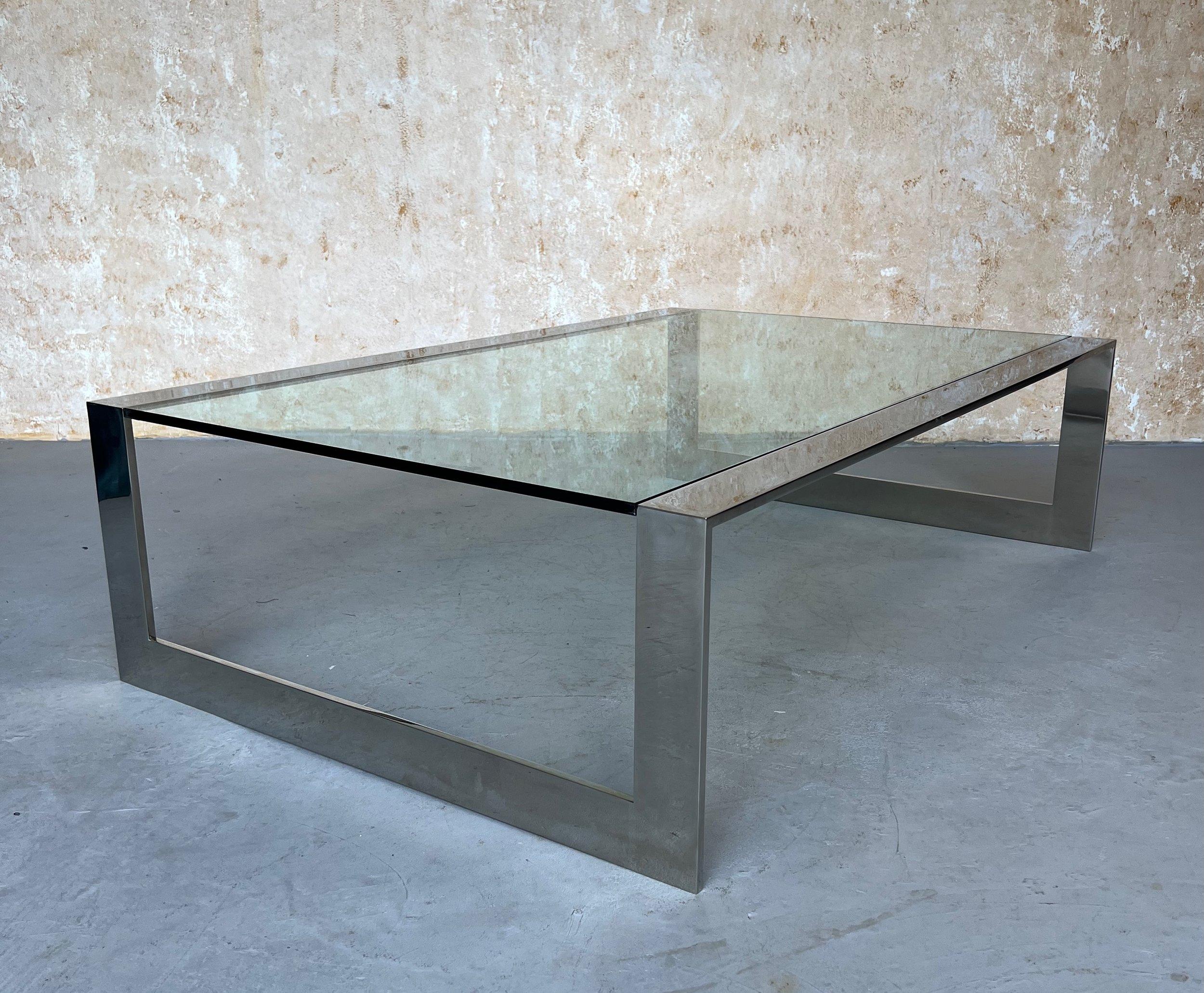 Questo moderno tavolino da caffè in acciaio inossidabile lucido degli anni '70 è dotato di un piano in vetro trasparente incastonato, che aggiunge un tocco elegante e contemporaneo a qualsiasi spazio abitativo. Con dimensioni di 15 pollici di