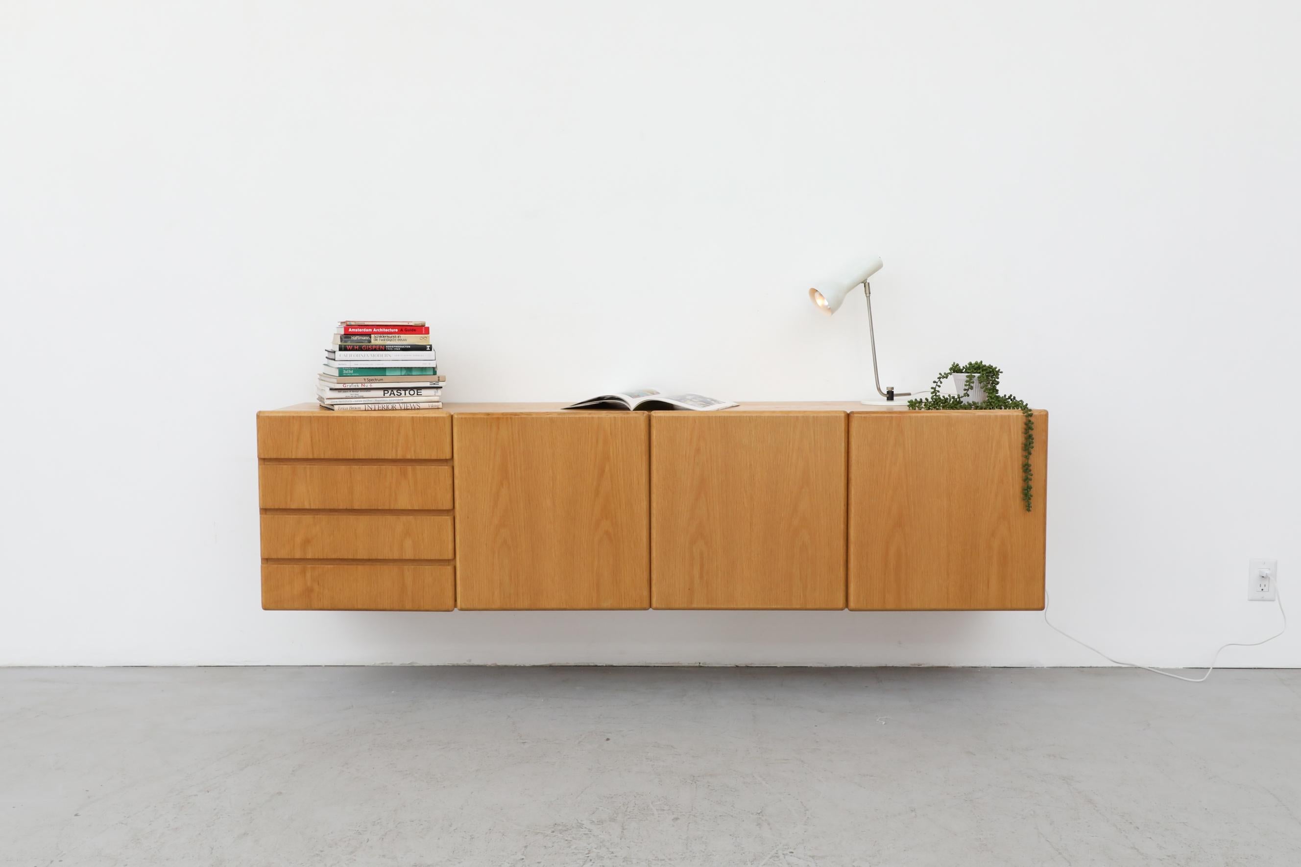 Sleek 70's floating wall mount oak credenza. The shelves in the cabinets measure 18.5 x 15.875 x 9 and the drawers measure 16.25 x 13.75 x 2.5 each. In original condition with some light wear, consistent with its age and use. Shot with a Hala (attr)