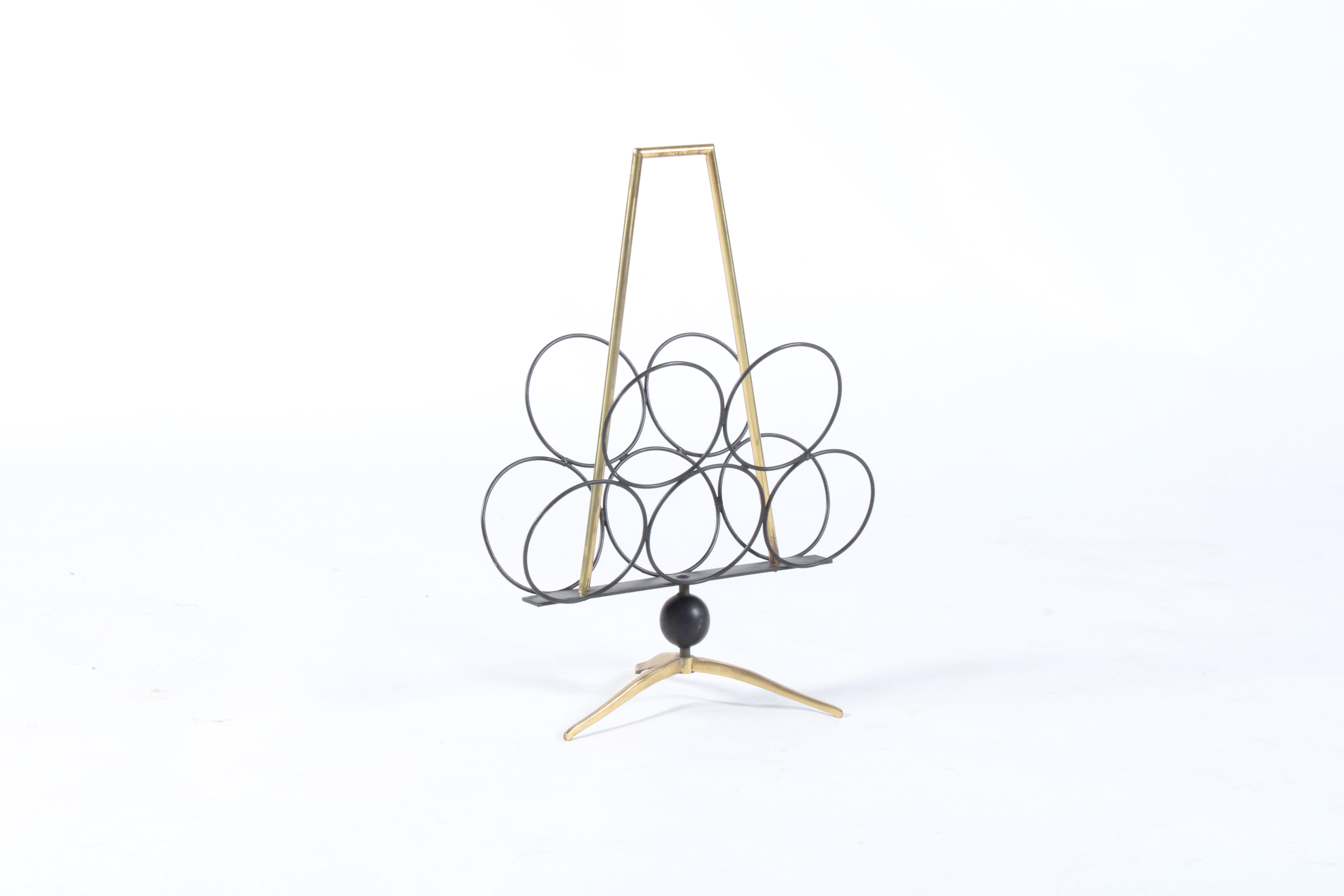 An exceptional original mid century Italian magazine rack. Hugely decorative and stylish this piece oozes mid century Italian sophistication and design. Made of welded brass on a tripod base the piece also features a decorative turned ebonized  