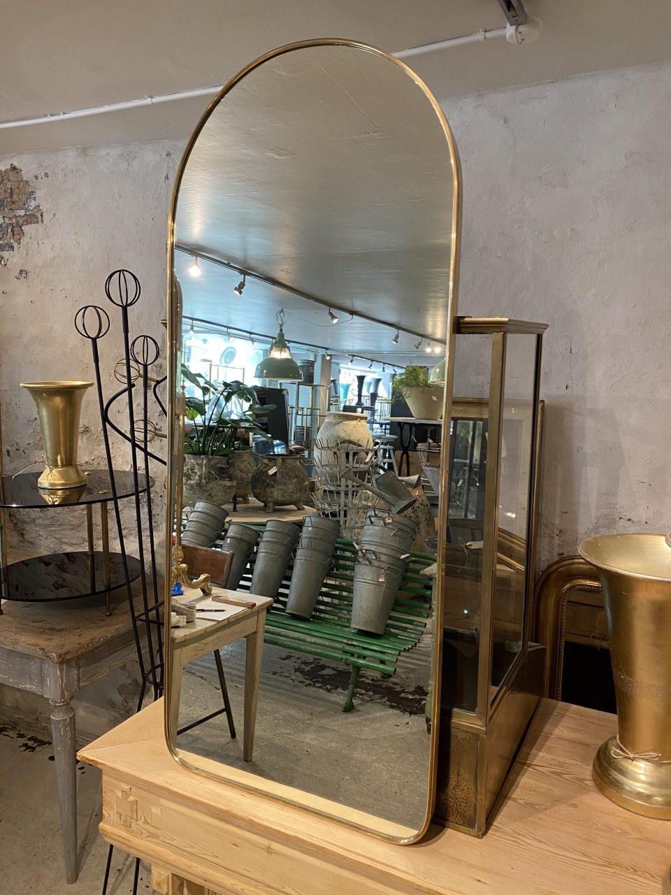 Stylish and sought after midcentury Italian brass mirror, in a beautiful archway design. Original mirrored glass, and stylistically related to the well-known designer Giò Ponti. There are suspension brackets mounted on the back.

Notice the