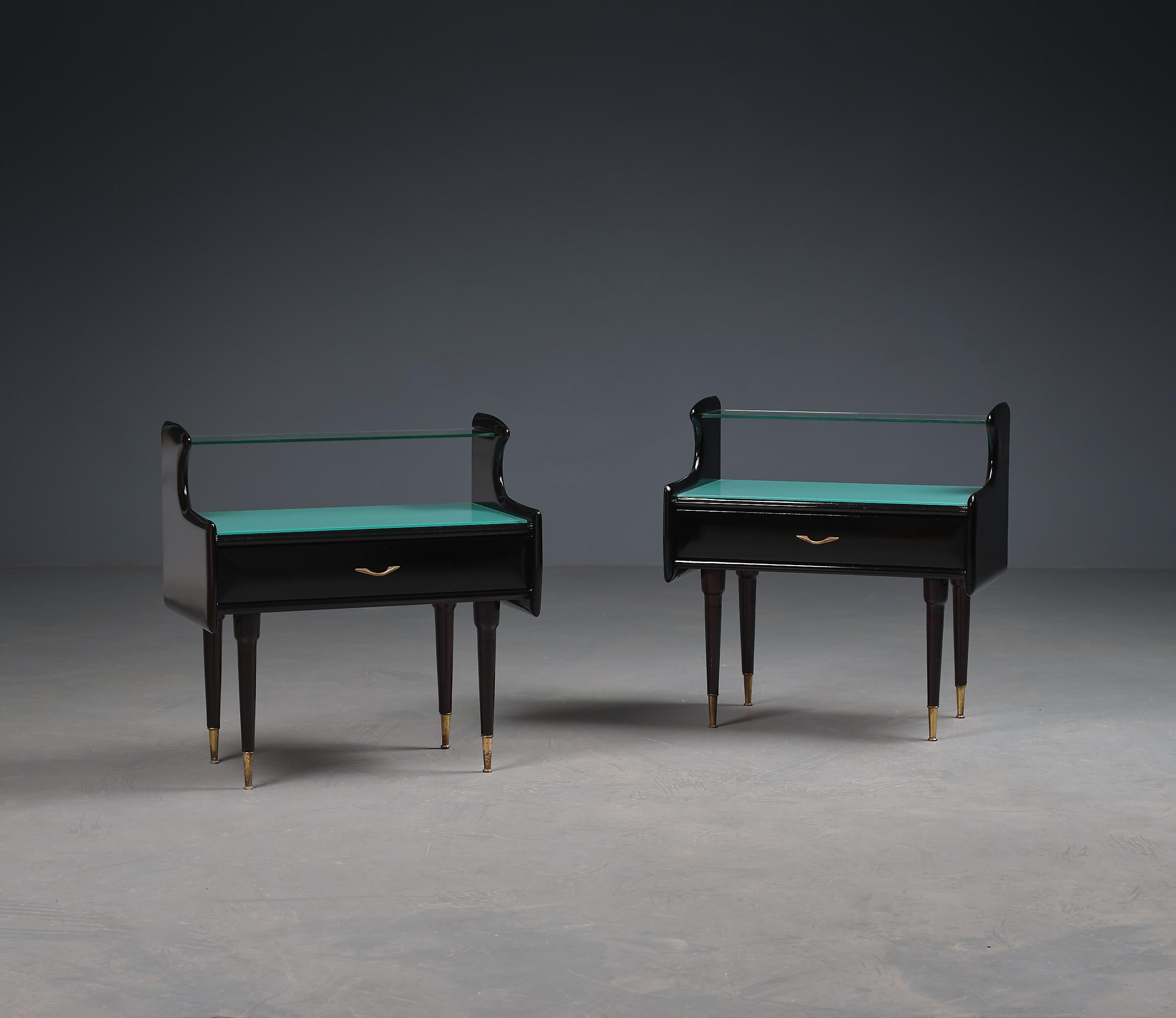 Cette paire sophistiquée de tables de nuit italiennes des années 1950 illustre les principes de design luxueux de l'ère du milieu du siècle. Récemment rénovées avec une nouvelle finition en laque noire de haute qualité, ces tables de nuit brillent