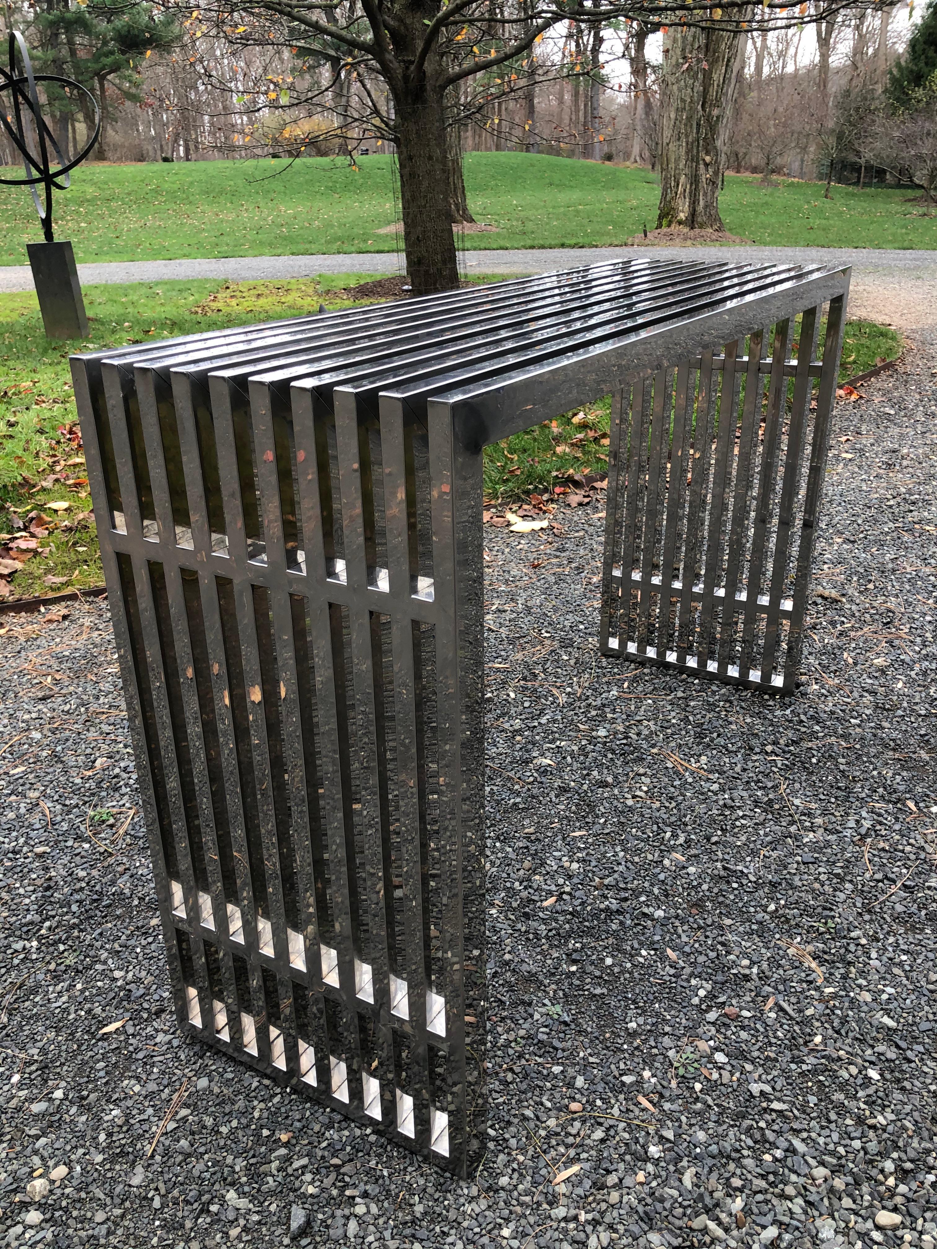 A Mid-Century Modern console or sofa table in the style of Theo Eichholtz. The chrome table features a rectangular profile with an architectural slanted line pattern.