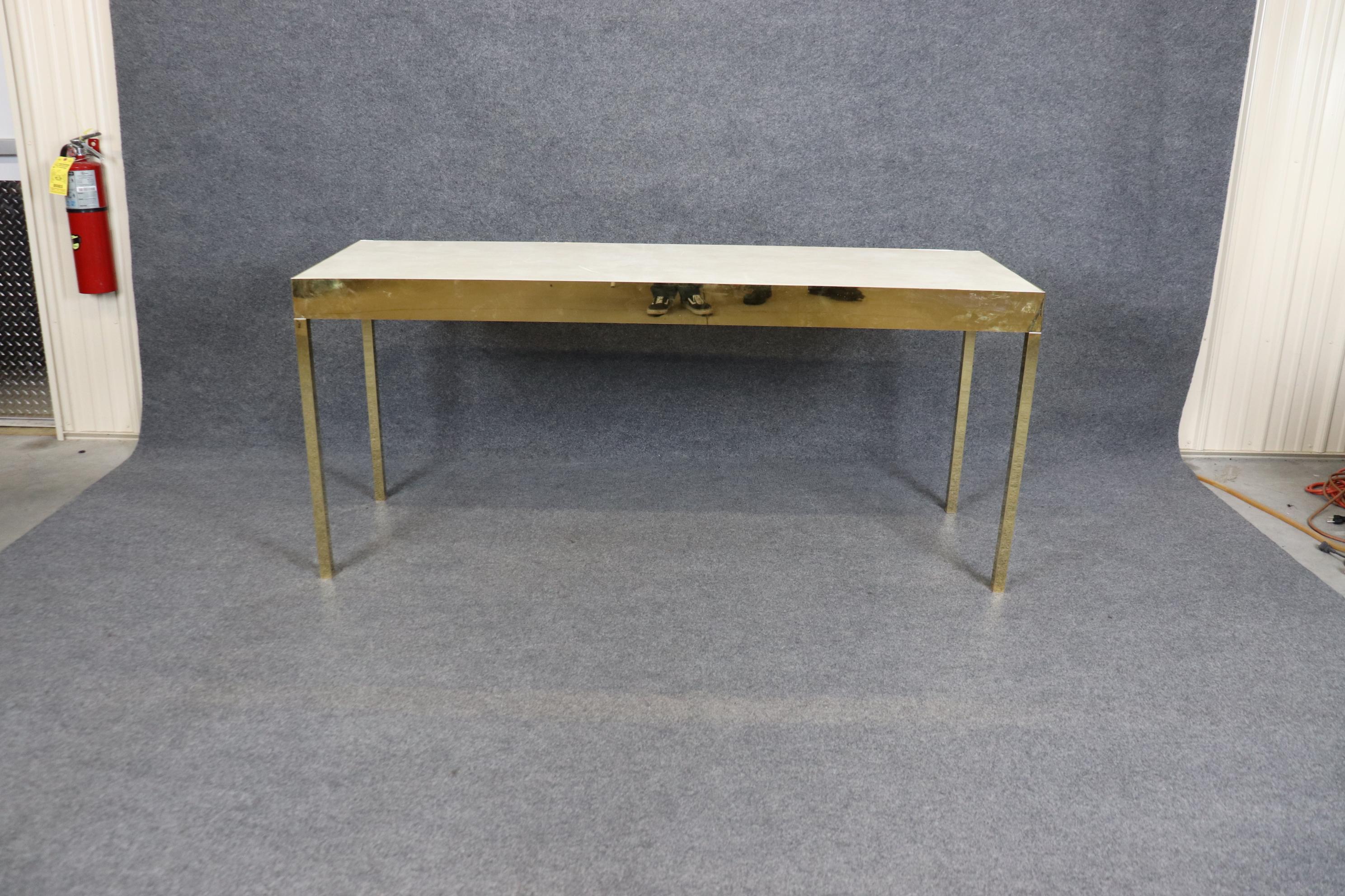 This table is a very sleek and modern style table similar to Milo Baughman in style. The table is in good condition with brass flashed metal and a leather top with age appropriate surface wear and signs of use.  Measures 71 wide x 23.75 deep x 31.5