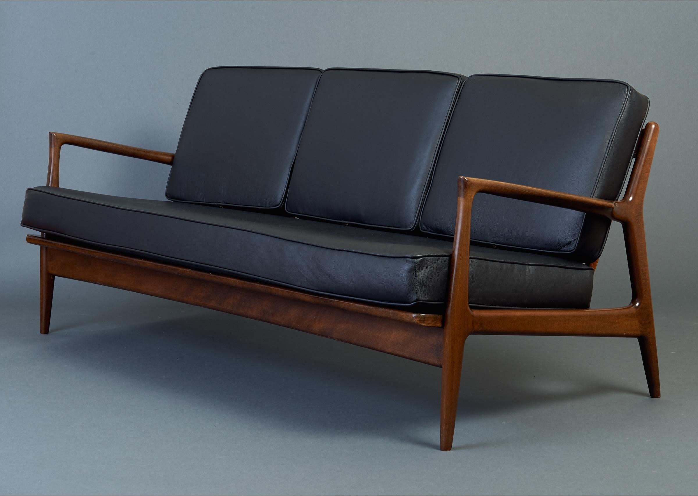 Ib Kofod-Larsen (1921–2003)

Sculptural sofa by Hans Wegner contemporary Ib Kofod-Larsen, for Selig. With graceful mahogany stained teak frame, biomorphic winged armrests, beautifully modeled back slats, and cushions newly upholstered in black