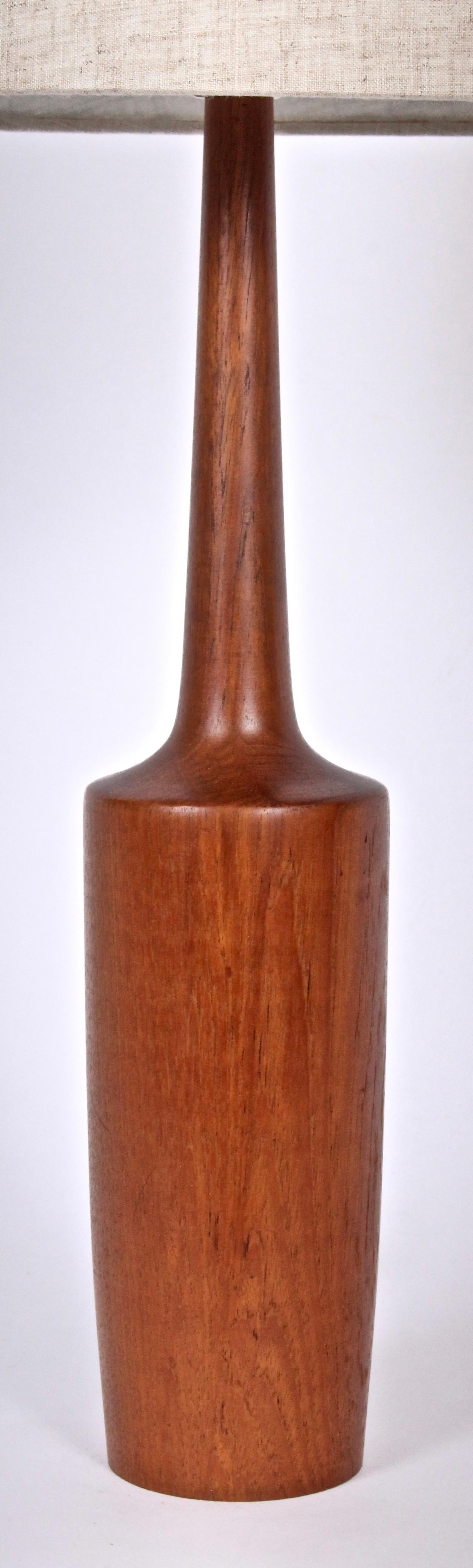 Slim Scandinavian Modern balanced solid teak table lamp, bedside lamp. Featuring a vividly grained, slender, bowling pin form utilizing a single piece of teak. Small footprint. 20H to top of socket. Teak 17H. Shade shown for display only (9 H x 11 D