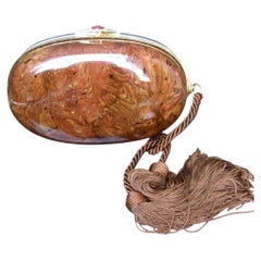 Elegante bolso de mano ovalado italiano de lucita color ámbar con borlas, de los años 70 aproximadamente
