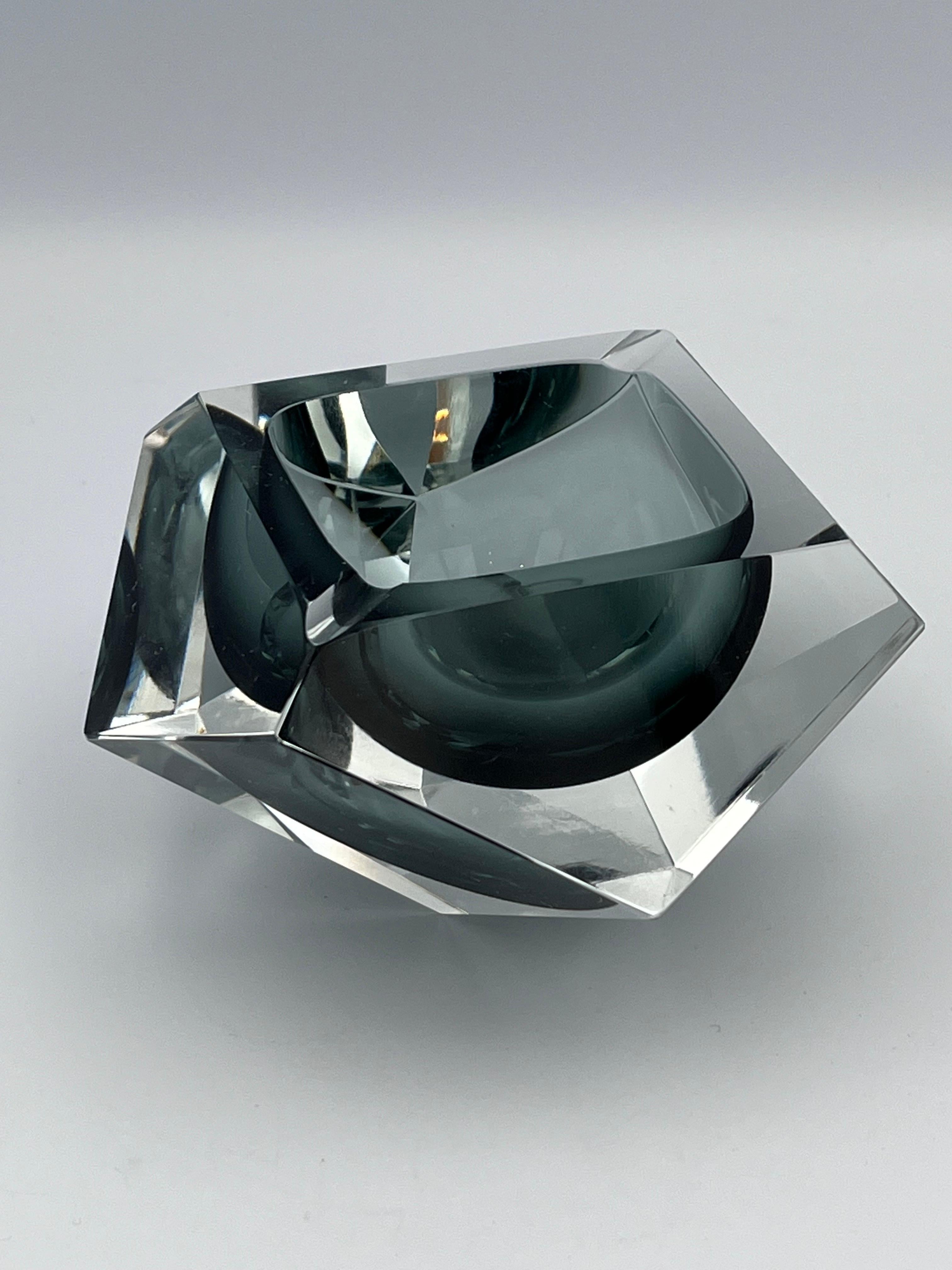 Questo splendido posacenere in cristallo del Mid Century Jewell's ha la rara forma di un tetradecagono (design a 14 lati), le cui sfaccettature dal taglio netto catturano la luce come un gioiello finemente tagliato. La geometria nitida dell'esterno